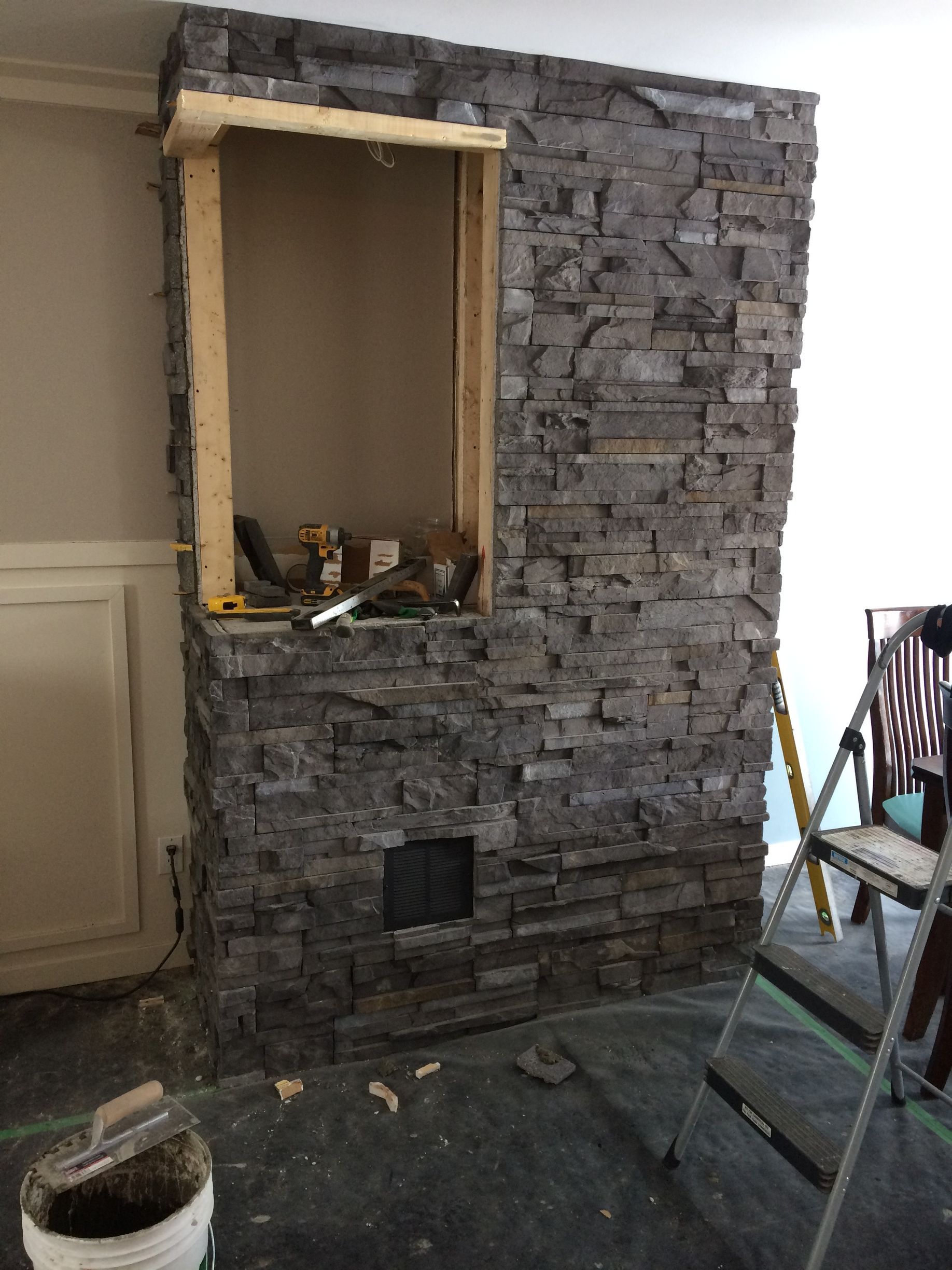 Une cheminée en pierre est en cours d'aménagement dans un salon.