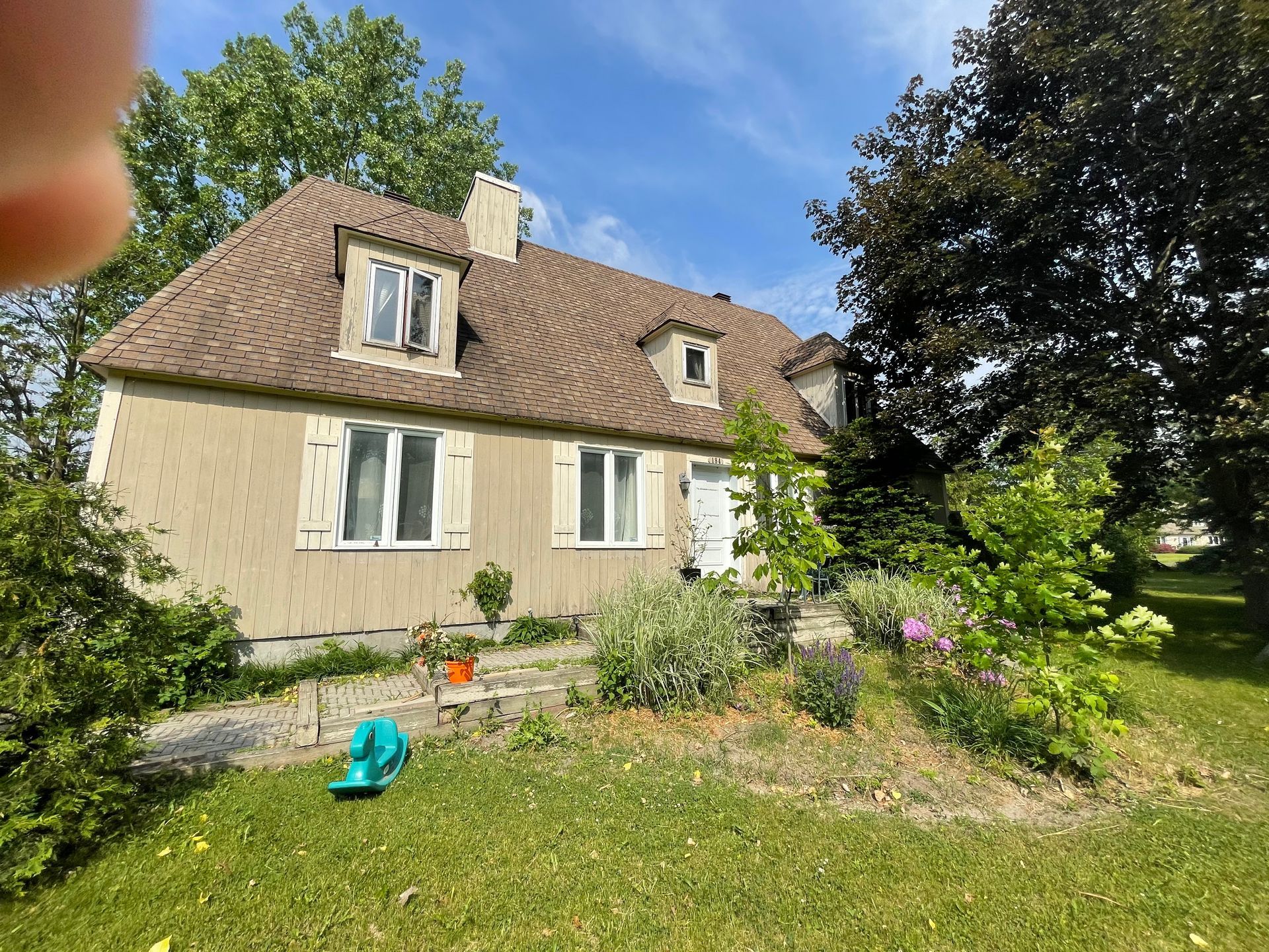Une personne prend en photo une maison avec un jardin devant.