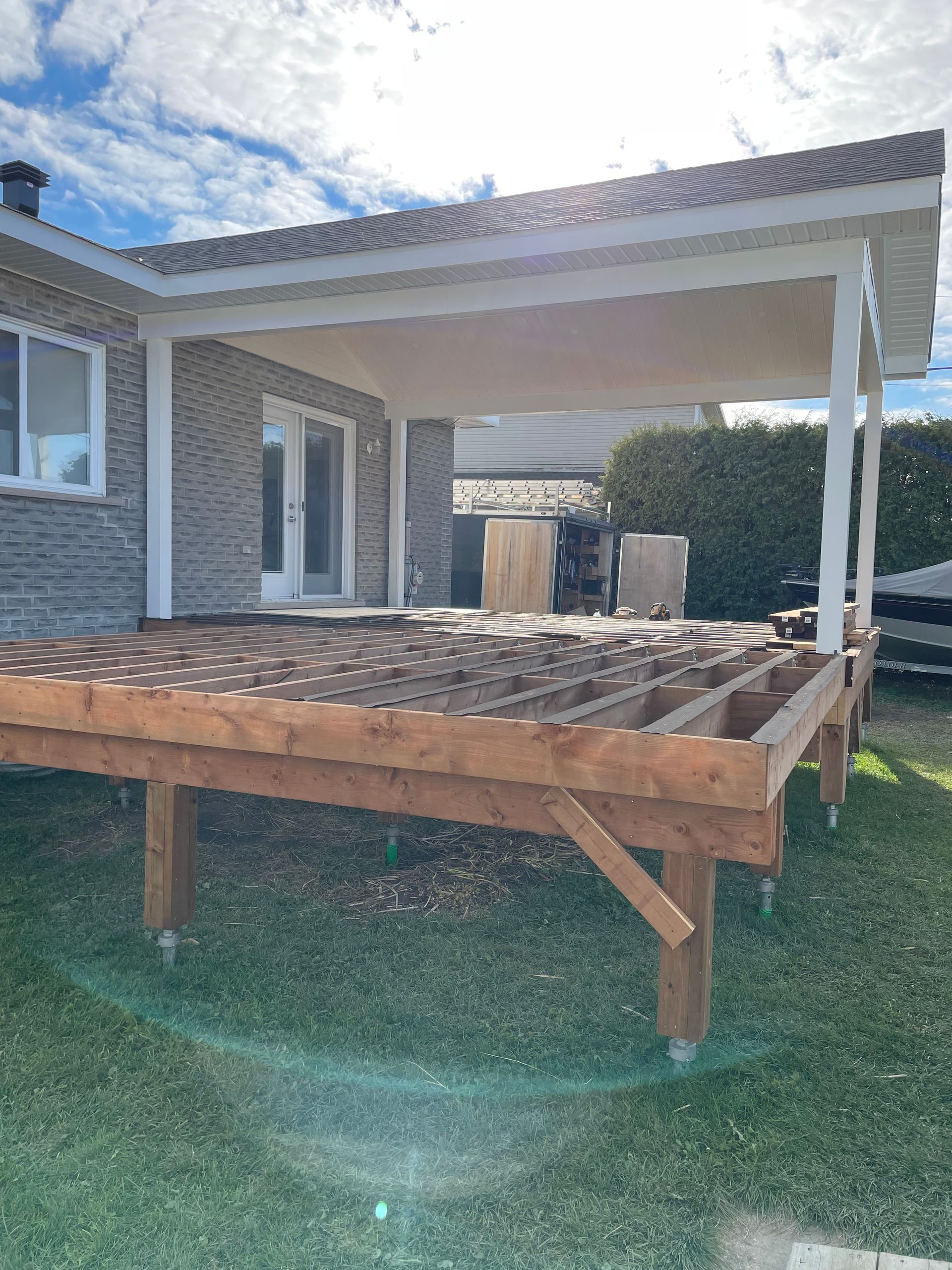 Une terrasse en bois est en cours de construction devant une maison.