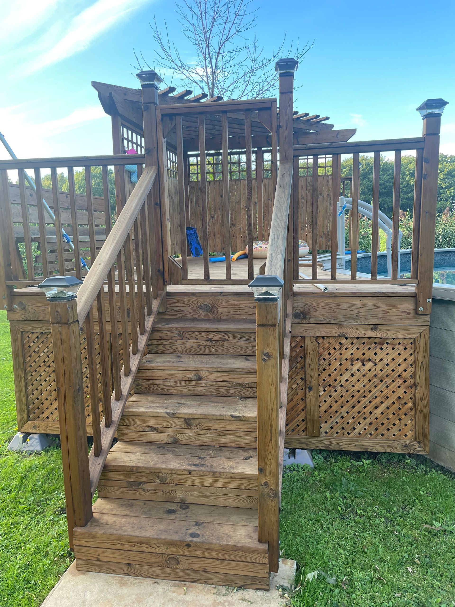 Une terrasse en bois avec des escaliers qui y mènent et un gazebo.