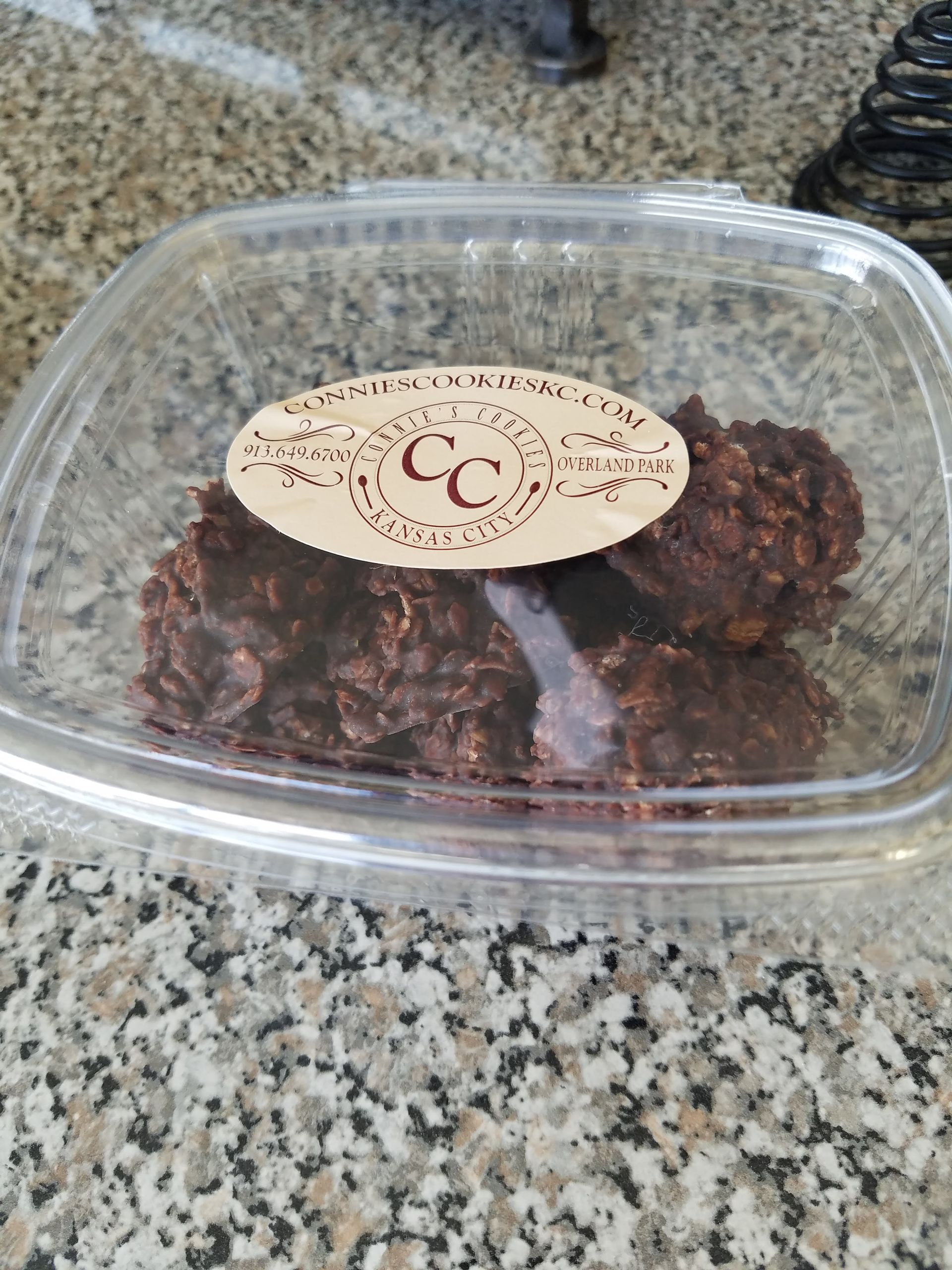 A plastic container filled with chocolate cookies is sitting on a counter.