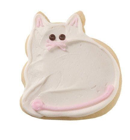 A cookie in the shape of a cat with white frosting and a pink tail.