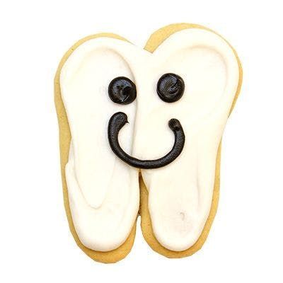 A cookie in the shape of a tooth with a smiley face on it.
