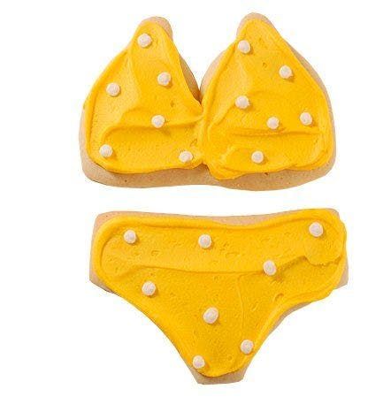 A cookie in the shape of a bikini with yellow frosting and white polka dots