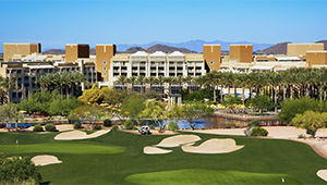 An aerial view of a golf course with a large building in the background.