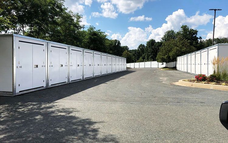 a row of white storage containers are lined up in a parking lot .