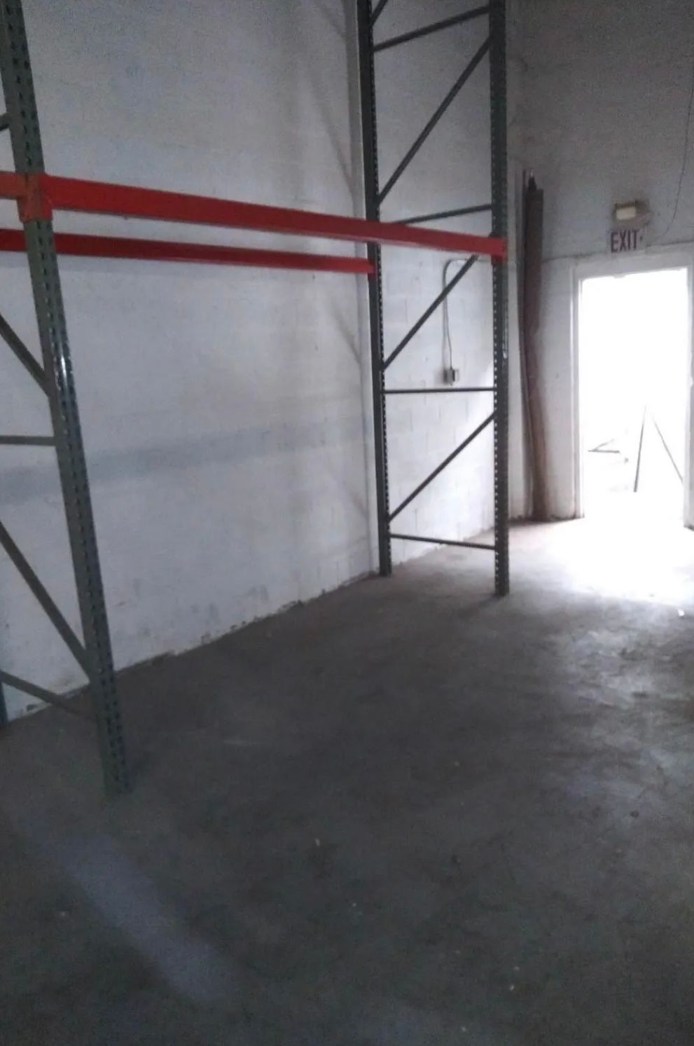An empty warehouse with a red railing and a door