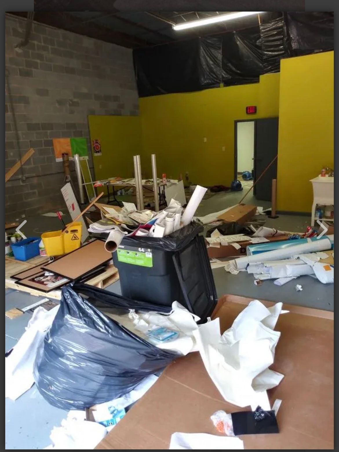 A messy room with a trash can that says ' recycle ' on it