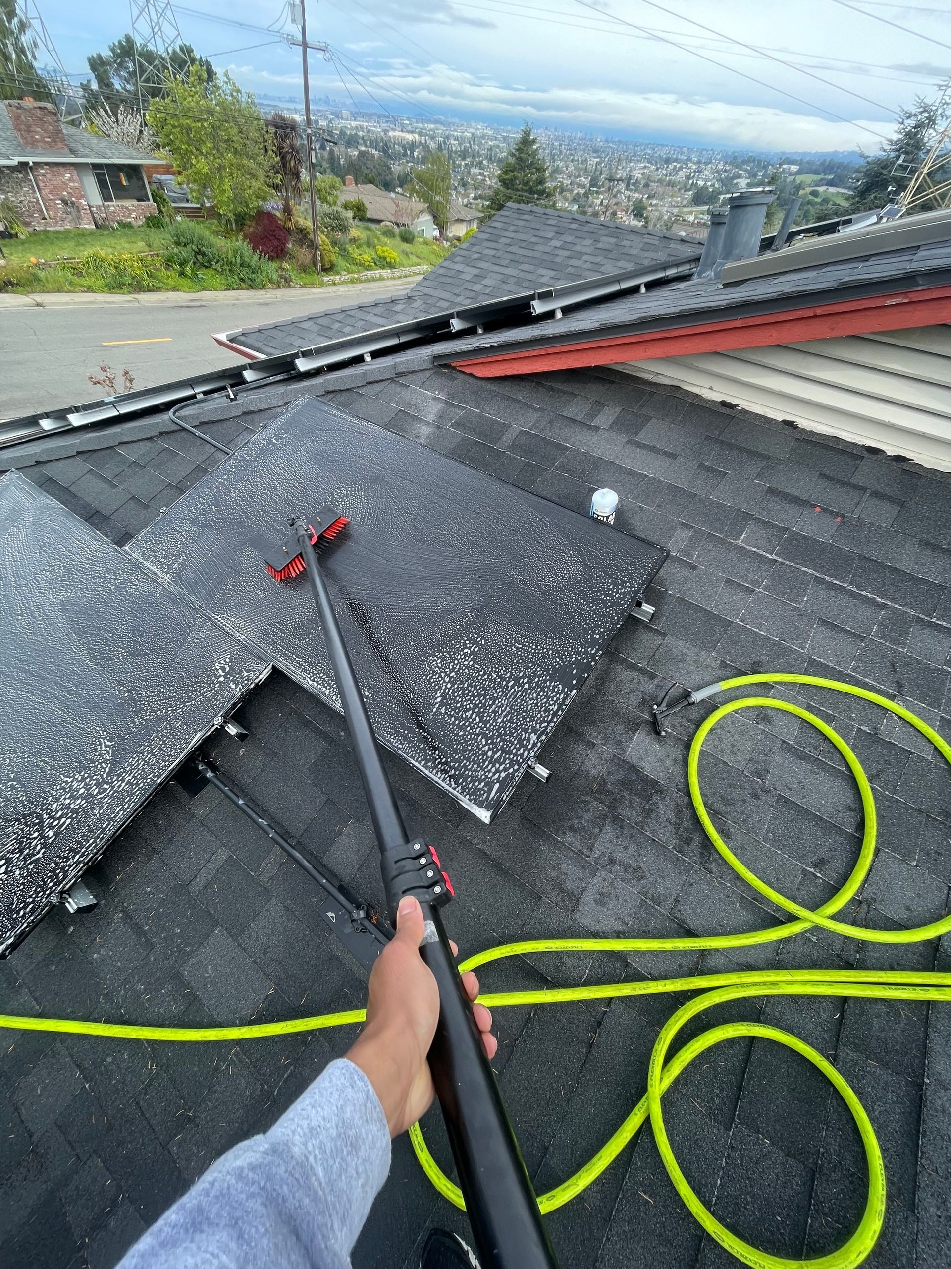 A person is cleaning the roof of a house with a hose.