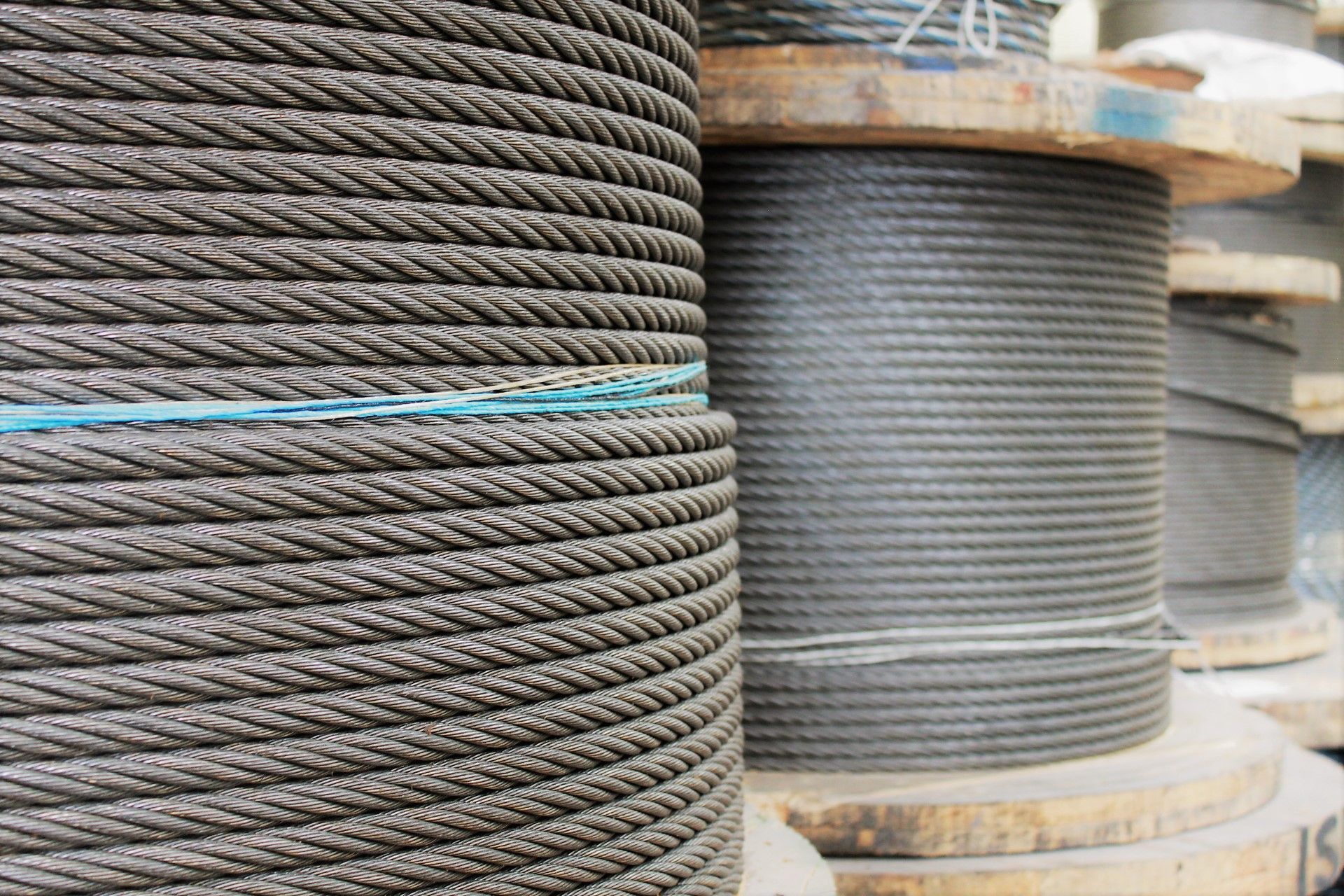 Carretes de cable de acero grueso y enrollado. Un primer plano muestra metal gris oscuro texturizado envuelto alrededor de tambores de madera.