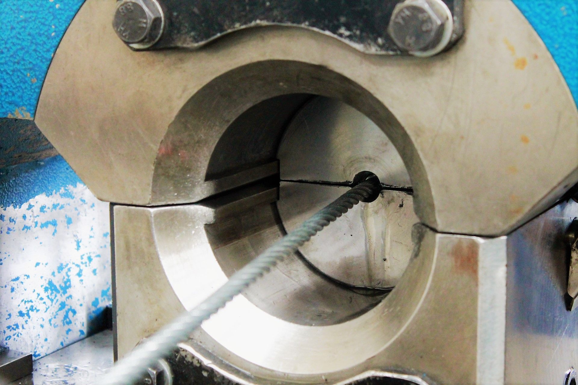 Cable de acero siendo engarzado en una máquina de metal, mostrando su núcleo central.