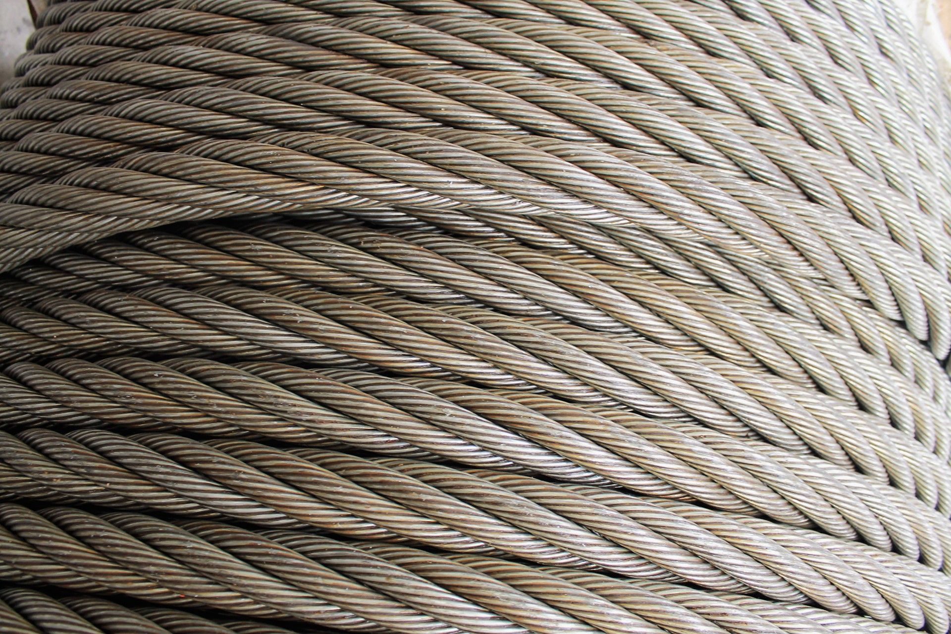 Cable de acero en espiral, fuertemente enrollado, con patrón diagonal y color gris metálico.