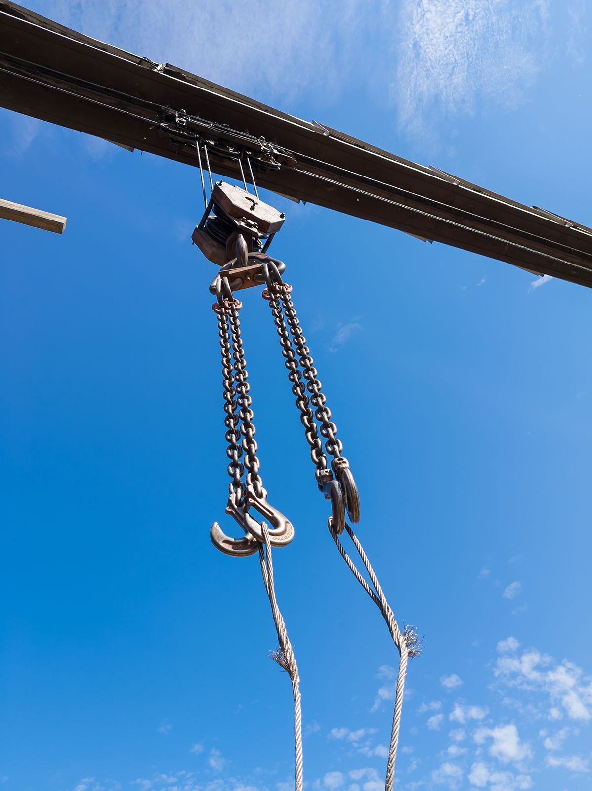 Un polipasto de cadena suspendido de una viga contra un cielo azul brillante.