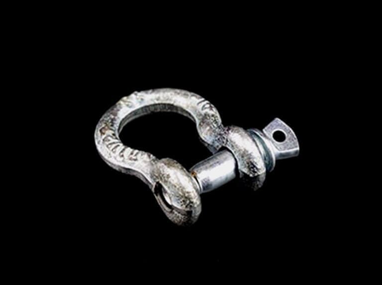 Grillete de metal plateado sobre fondo negro.