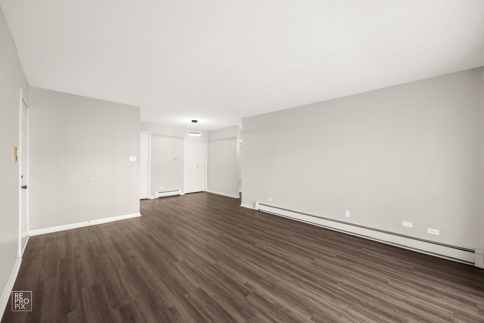 Empty room with dark wood-look flooring, light gray walls, and white trim.