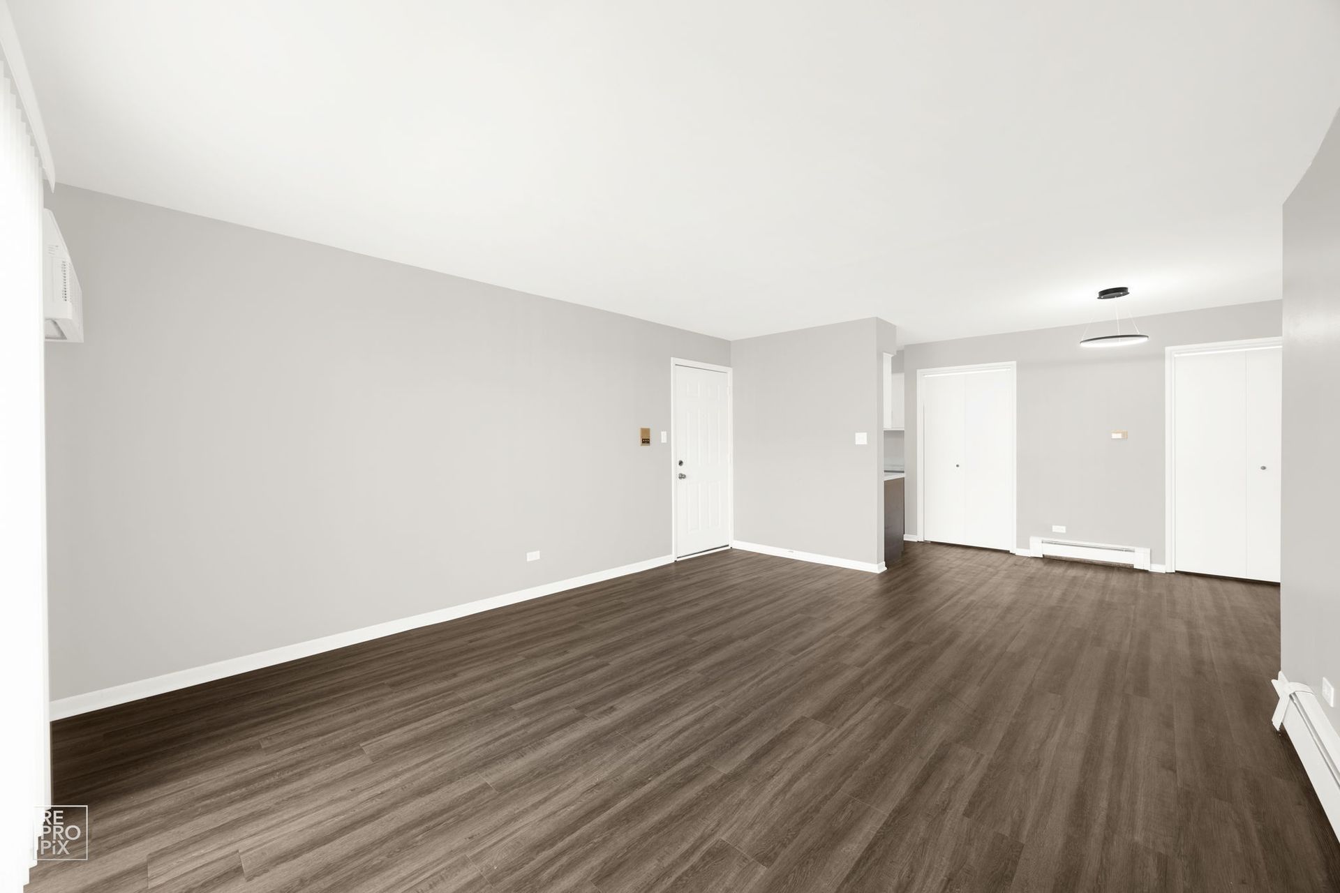 Empty living room with gray walls, dark wood floors, and white trim.