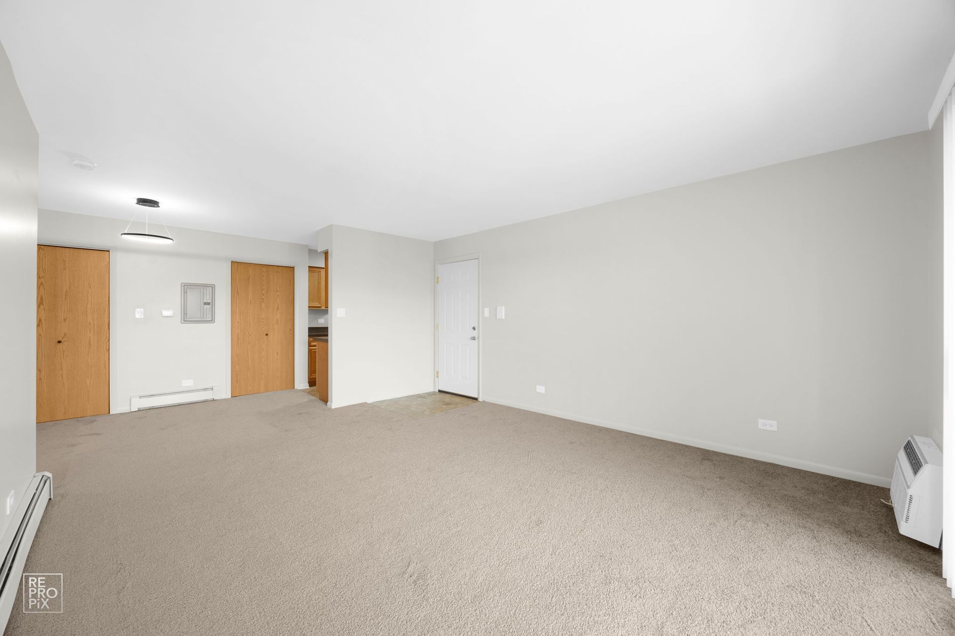Empty room with beige carpet, light gray walls, and wood doors.