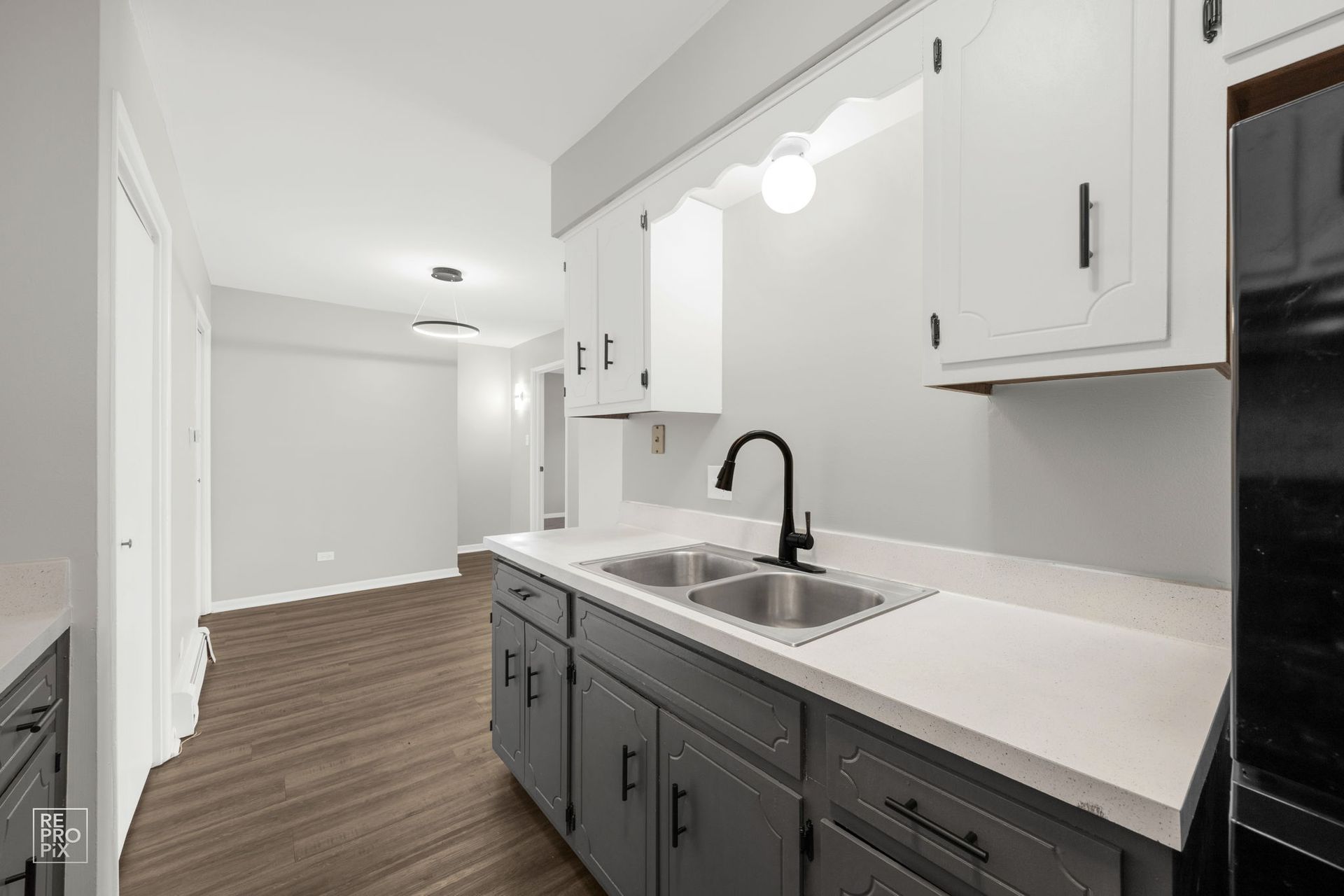 Kitchen with grey cabinets, white countertops, and a black faucet.