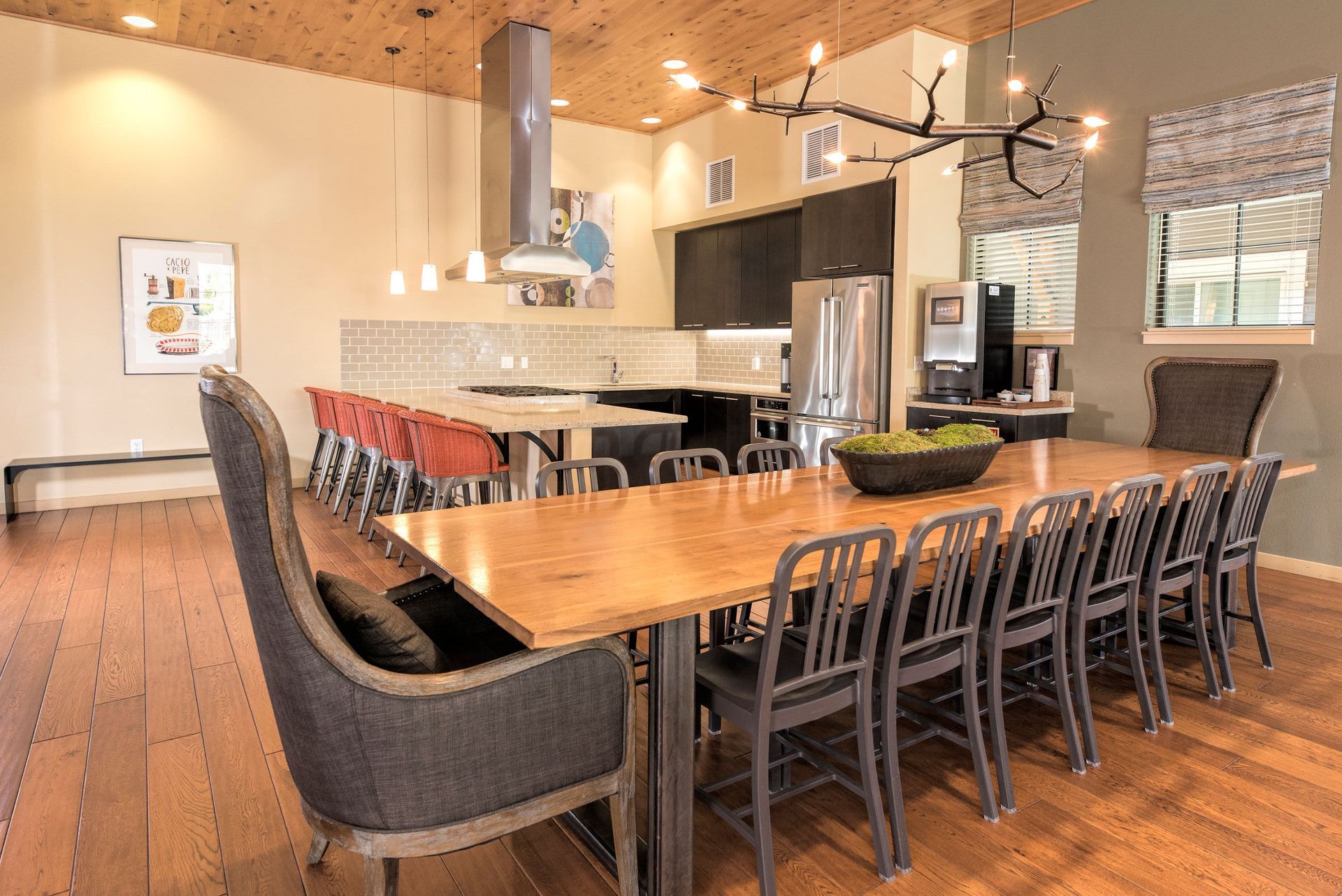 Communal kitchen and dining area with an island, stainless appliances, and modern lighting.