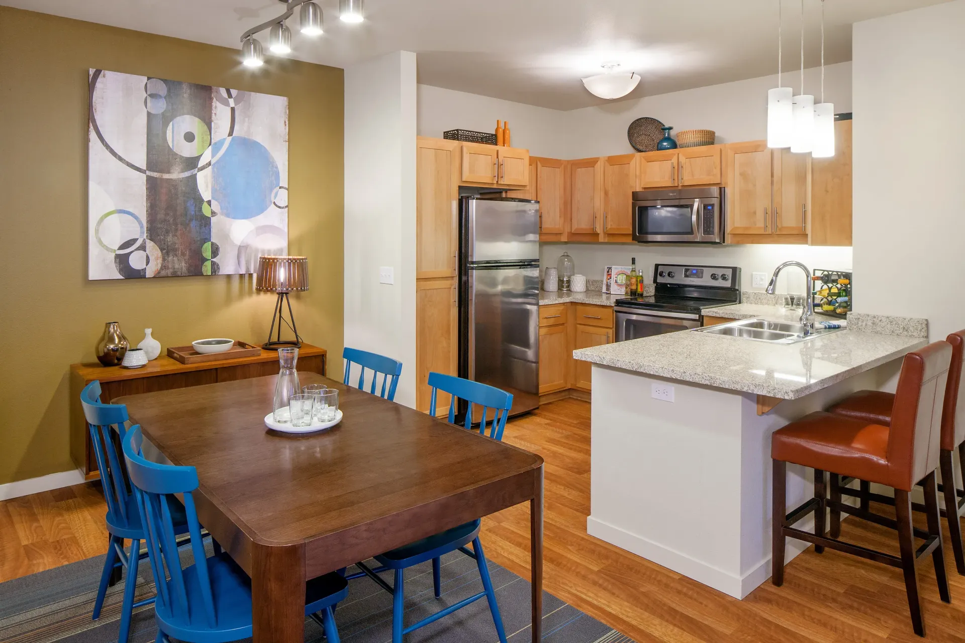 Open-concept kitchen and dining area with wooden cabinets, stainless-steel appliances, and granite countertops.