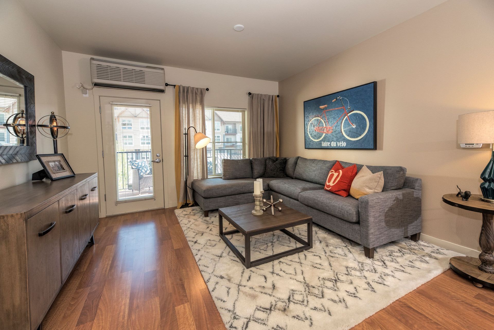 Living room in an apartment with a gray sectional sofa, coffee table, and rug.