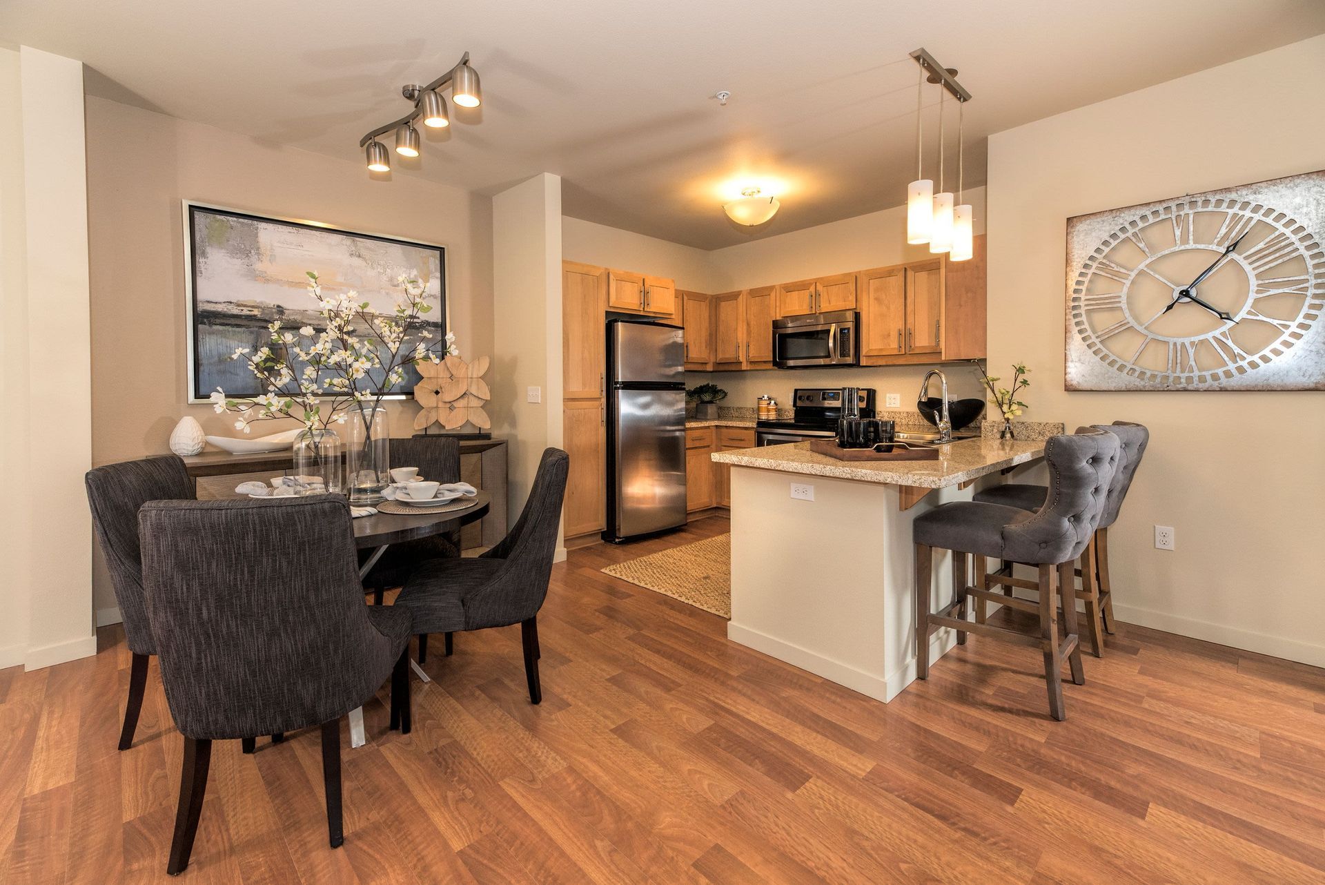 Open-concept apartment kitchen and dining area with island, wood flooring, and stainless appliances.