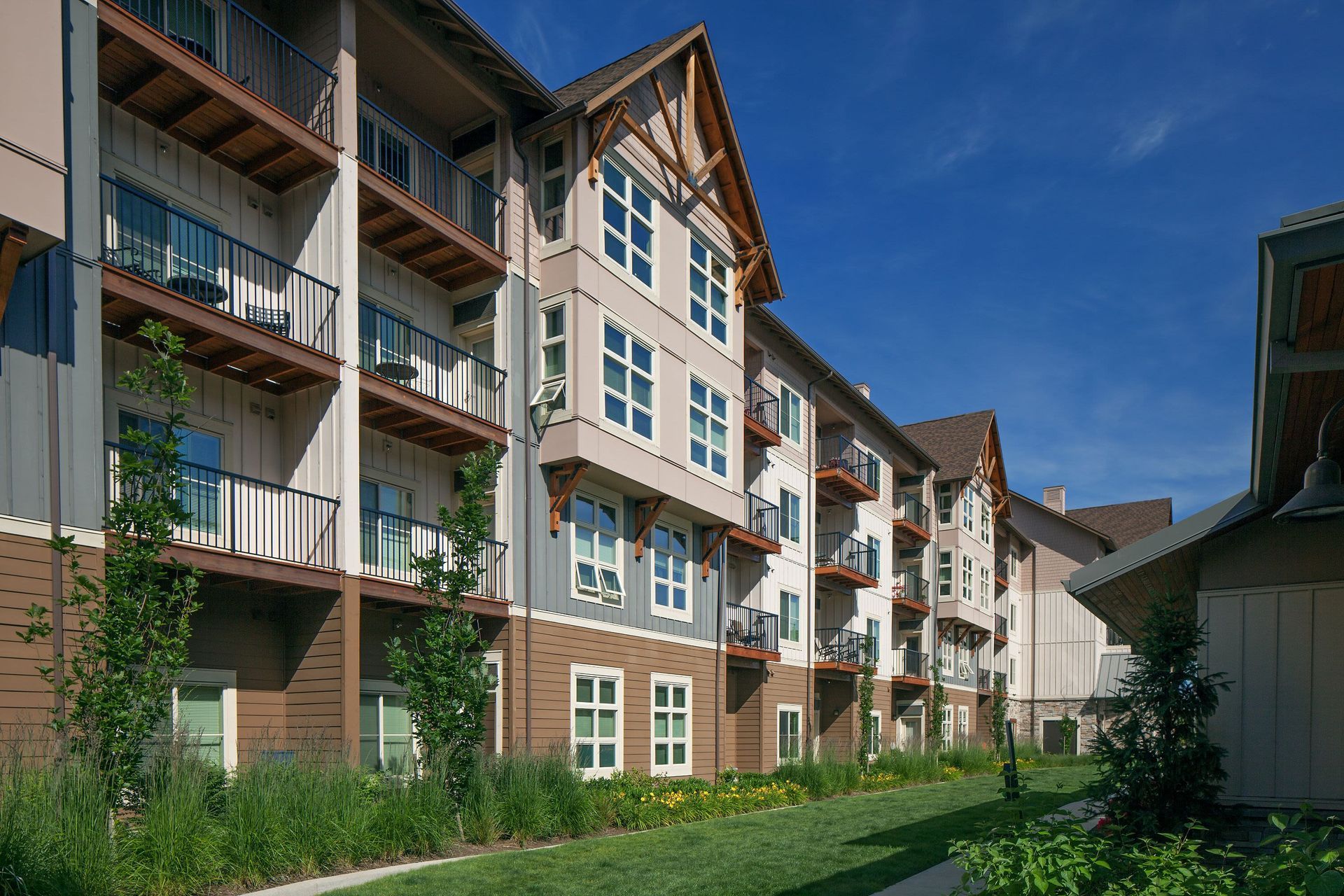 Exterior view of a modern apartment building with multiple balconies and landscaping.