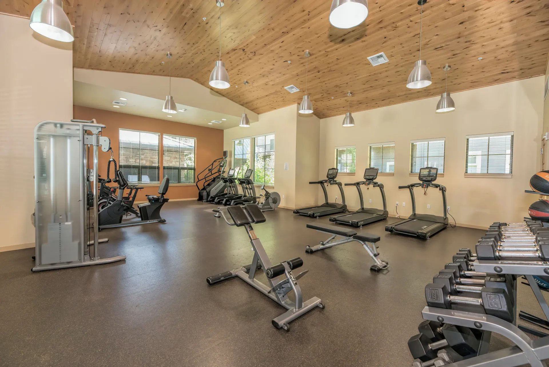 Well-lit fitness center with treadmills, stationary bikes, and free-weights area.