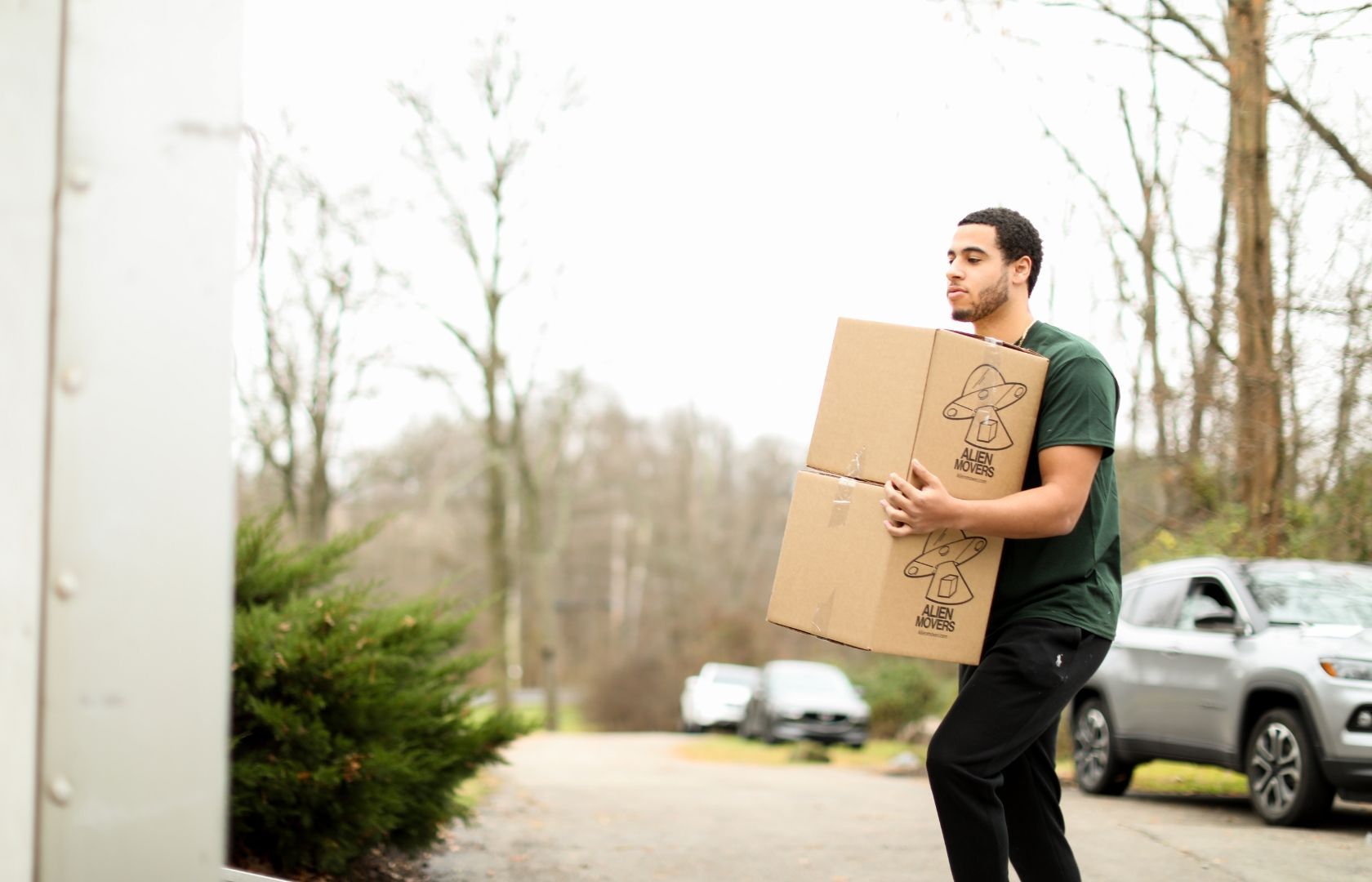 A smiling mover in a bright yellow shirt and black pants, holding moving equipment, stands ready at a storage facility, exemplifying efficient moving and packing services.