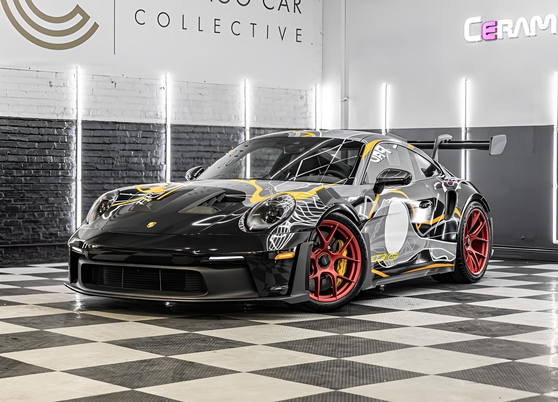 Black and yellow Porsche 911 GT3 with red wheels parked on a checkered floor.