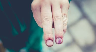 Un primer plano de la mano de una persona con uñas moradas.