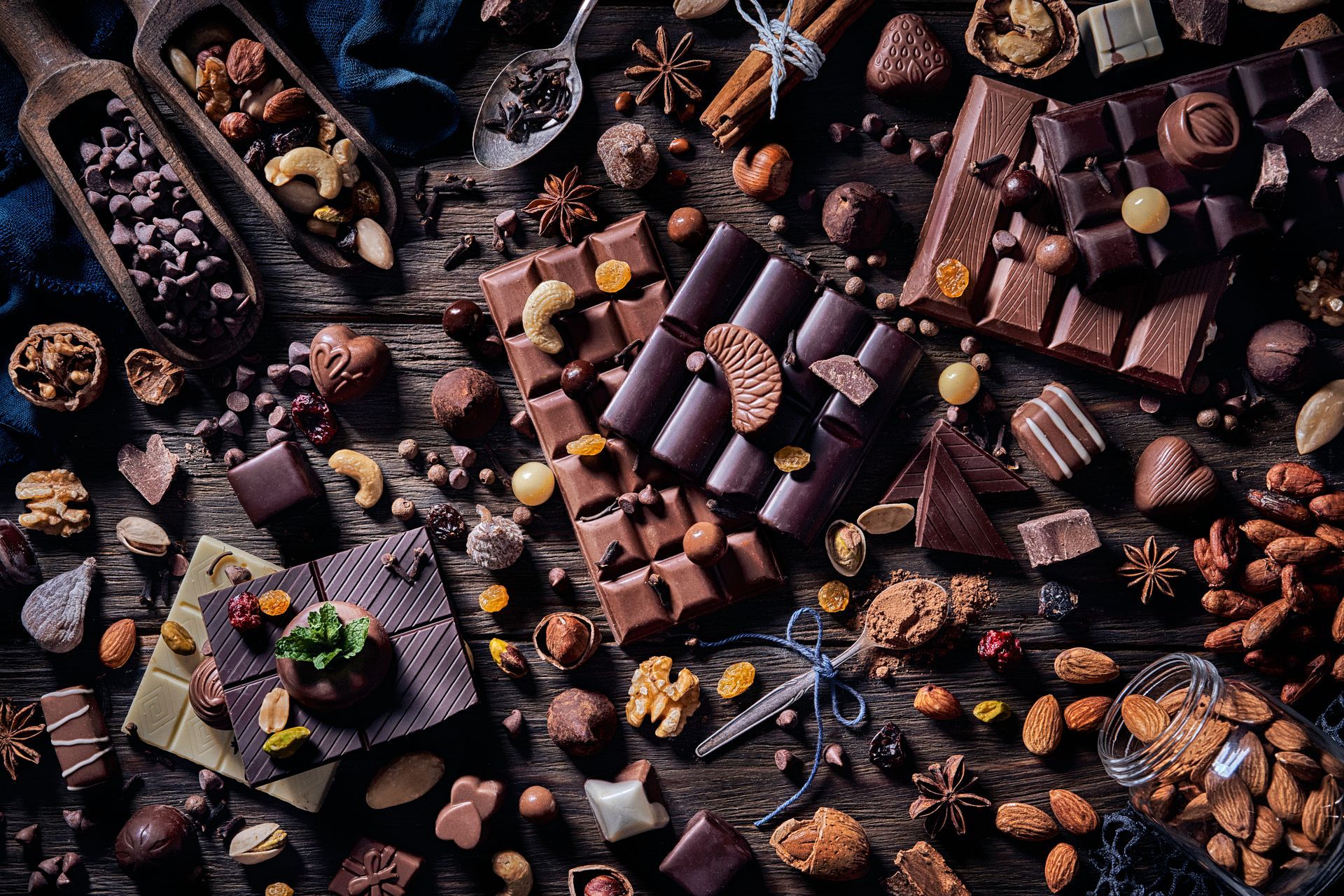 Chocolate and nuts arranged on a wooden surface, various shapes, textures, and shades of brown.