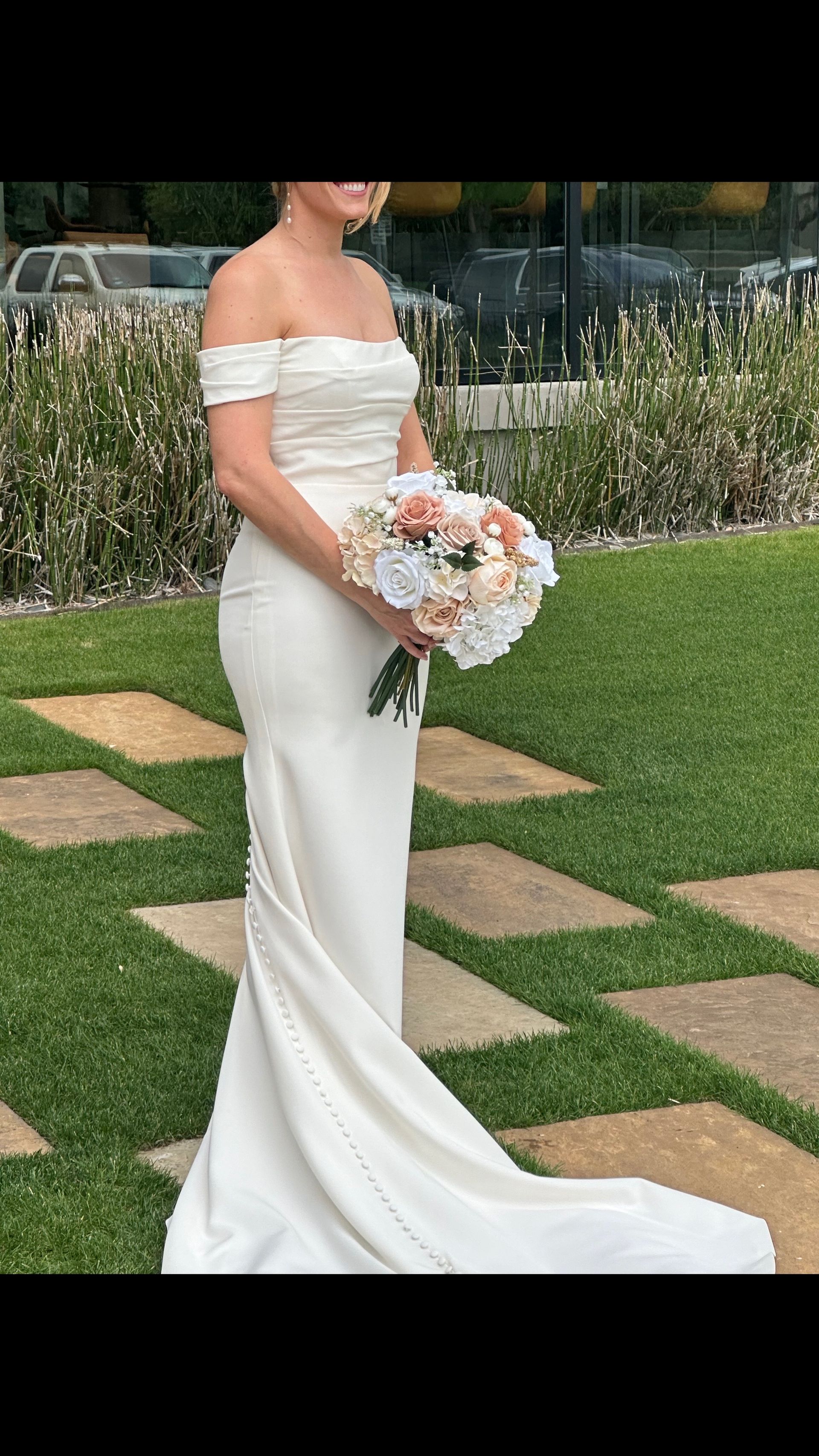 A woman in a white wedding dress is holding a bouquet of flowers.
