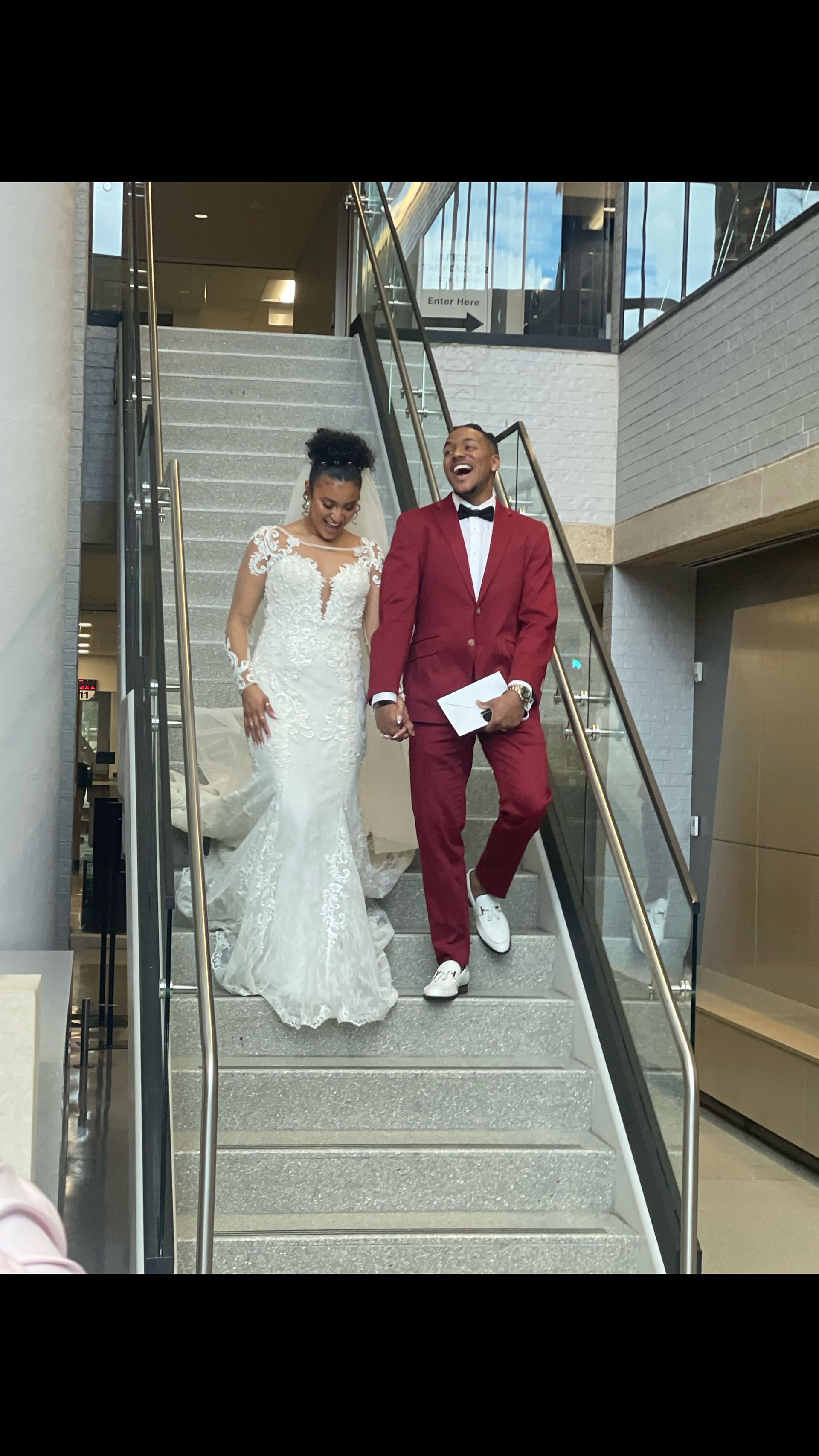 A bride and groom are walking down a set of stairs holding hands.