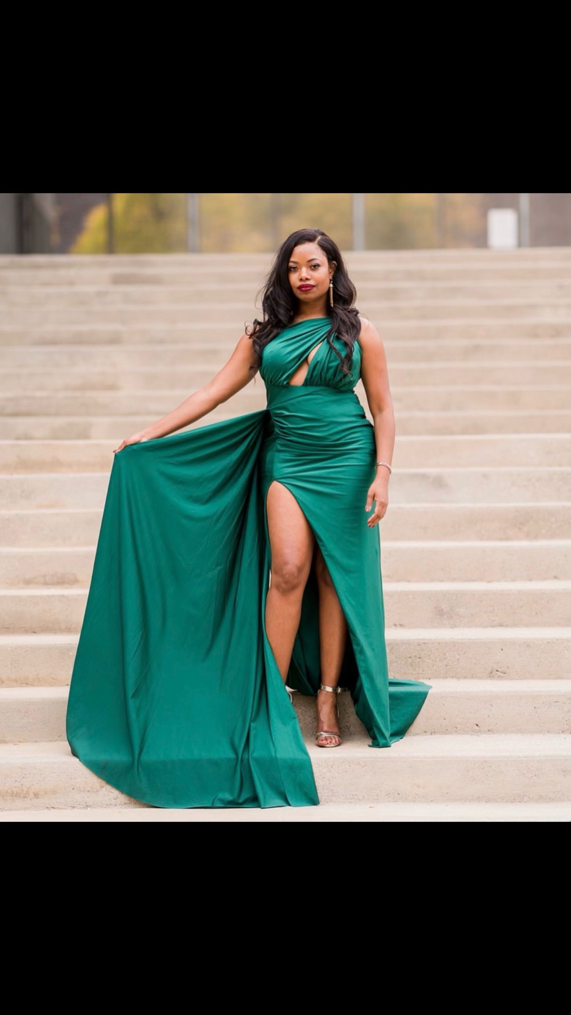 A woman in a green dress is standing on a set of stairs.