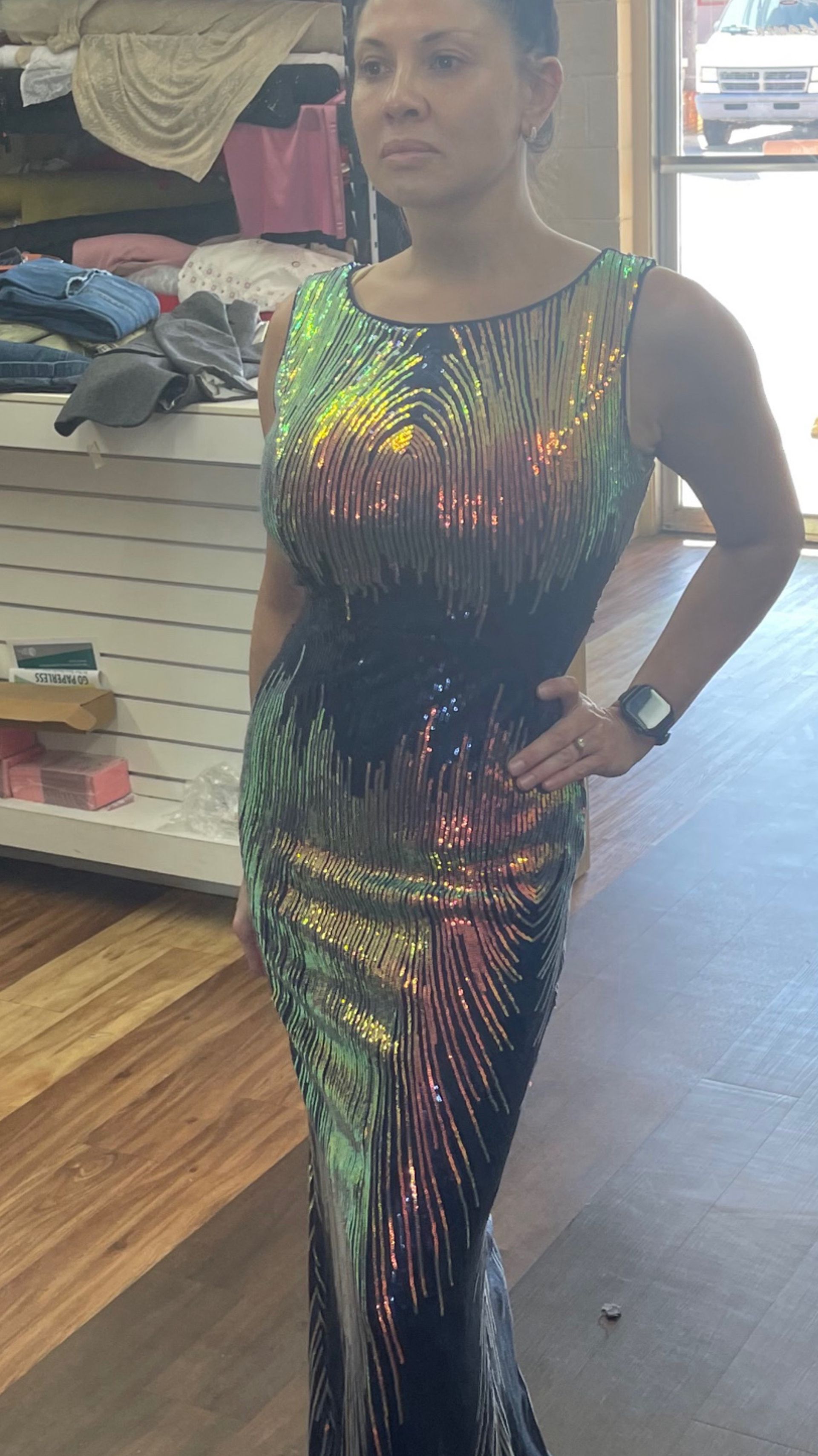 A woman is standing in a room wearing a sequined dress.