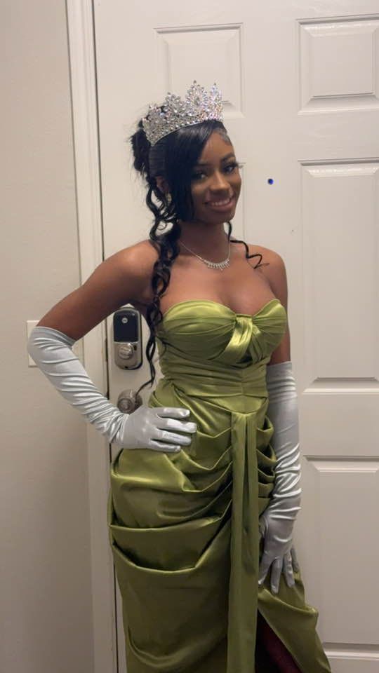 A woman in a green dress and gloves is standing in front of a door.