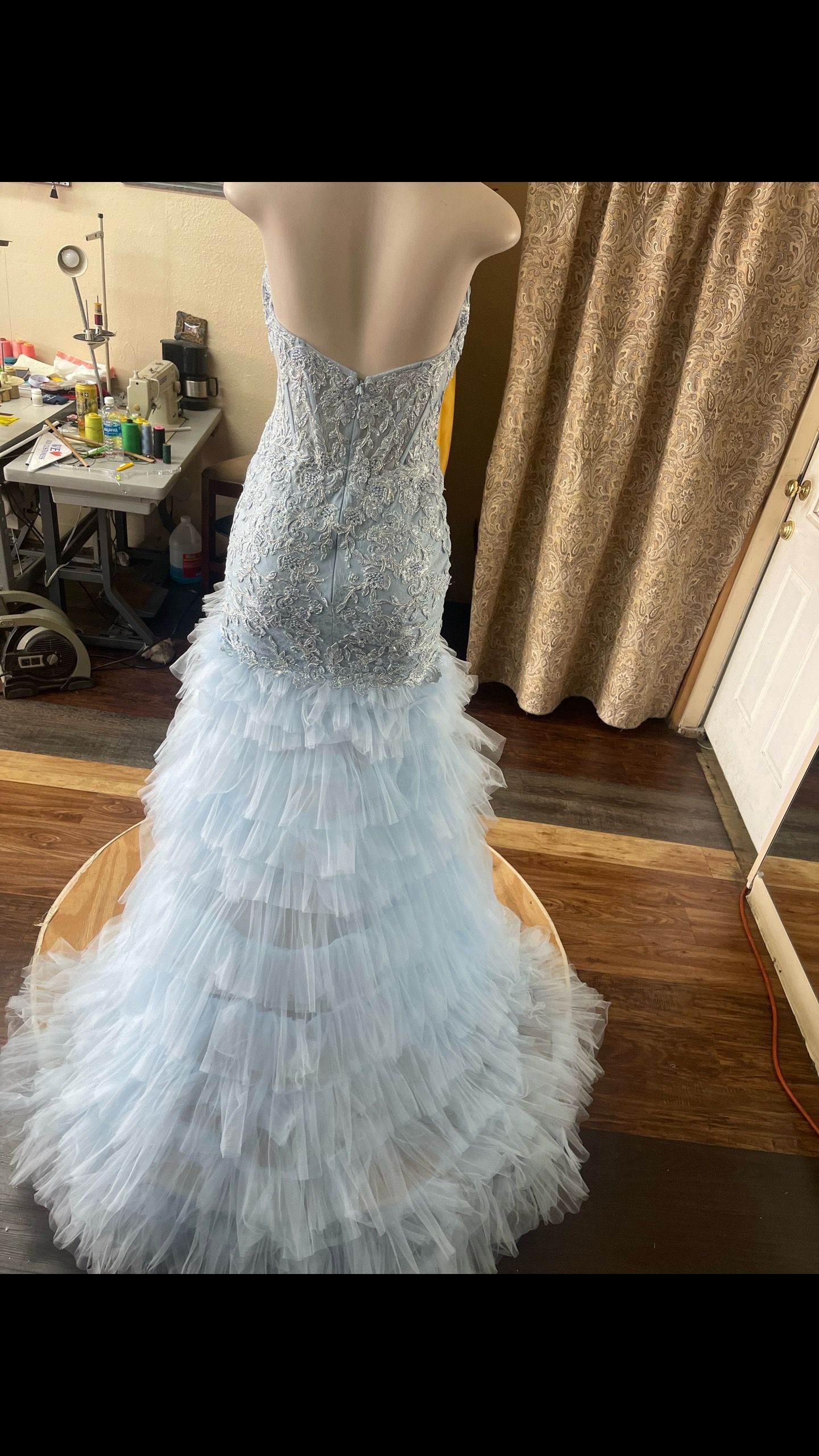 A white dress is on a mannequin in a room.