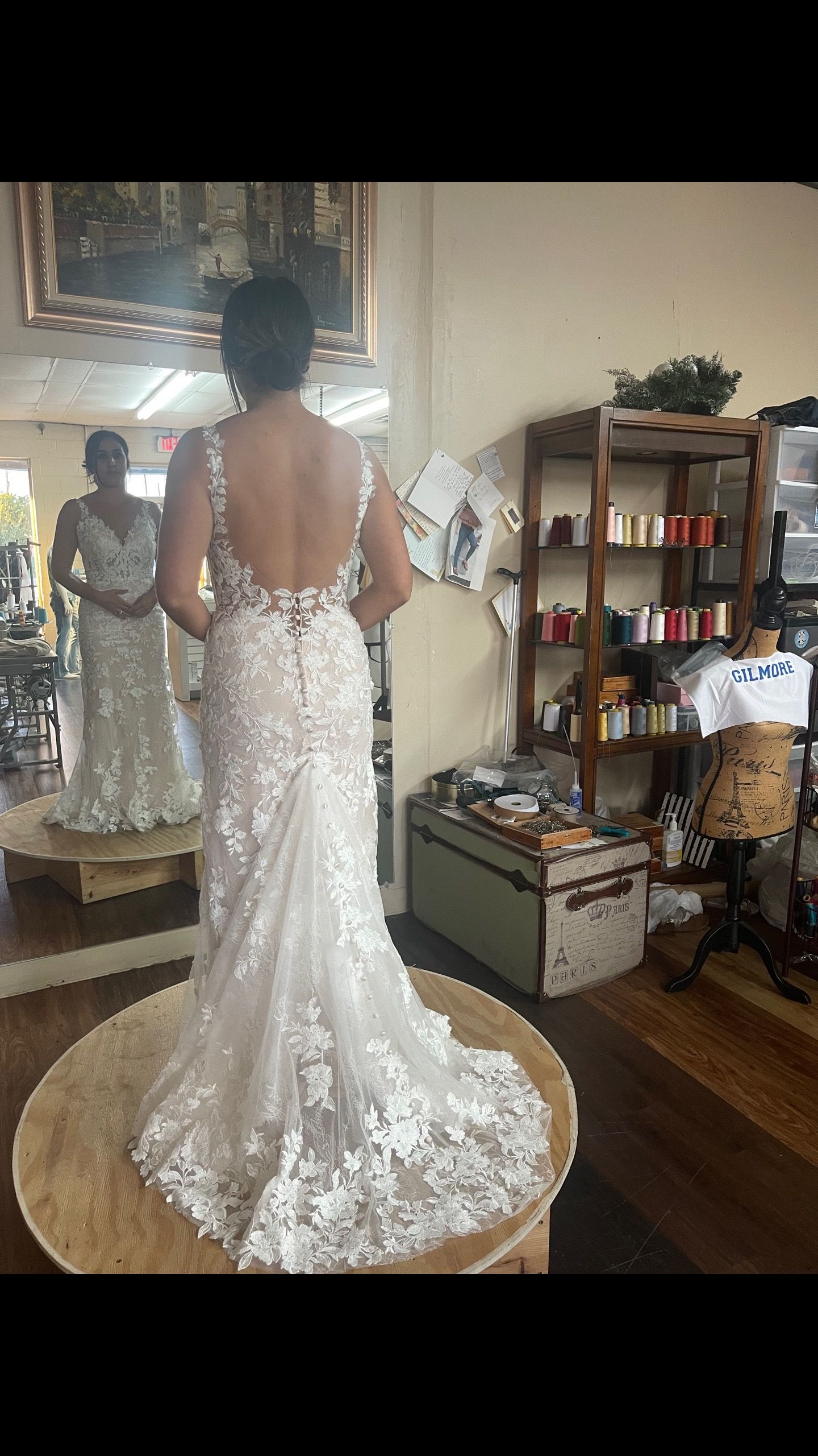 A woman is trying on a wedding dress in front of a mirror.