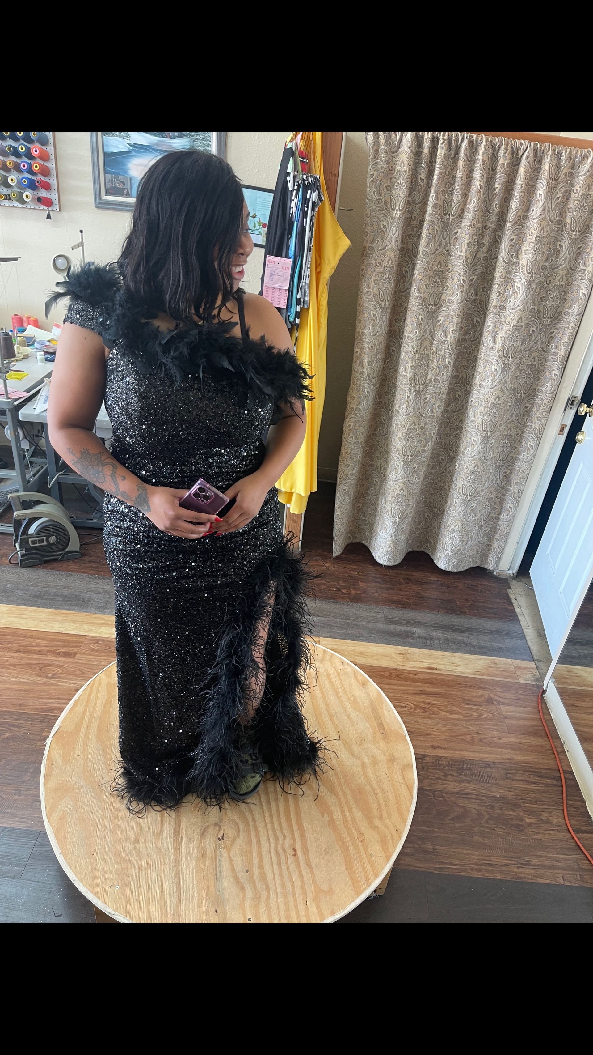 A woman in a black dress is standing on a wooden table in front of a mirror.