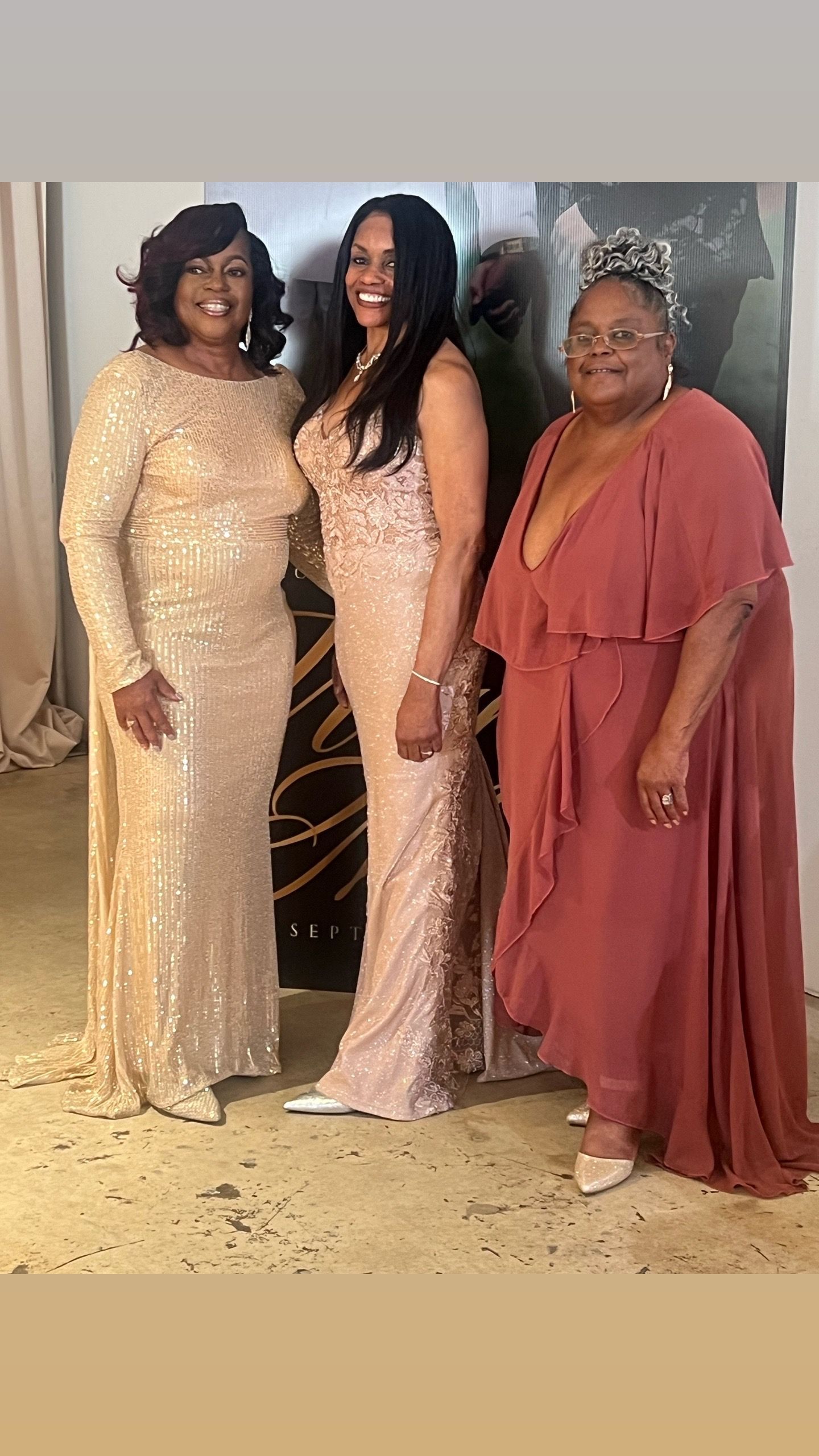 Three women in dresses are posing for a picture together.