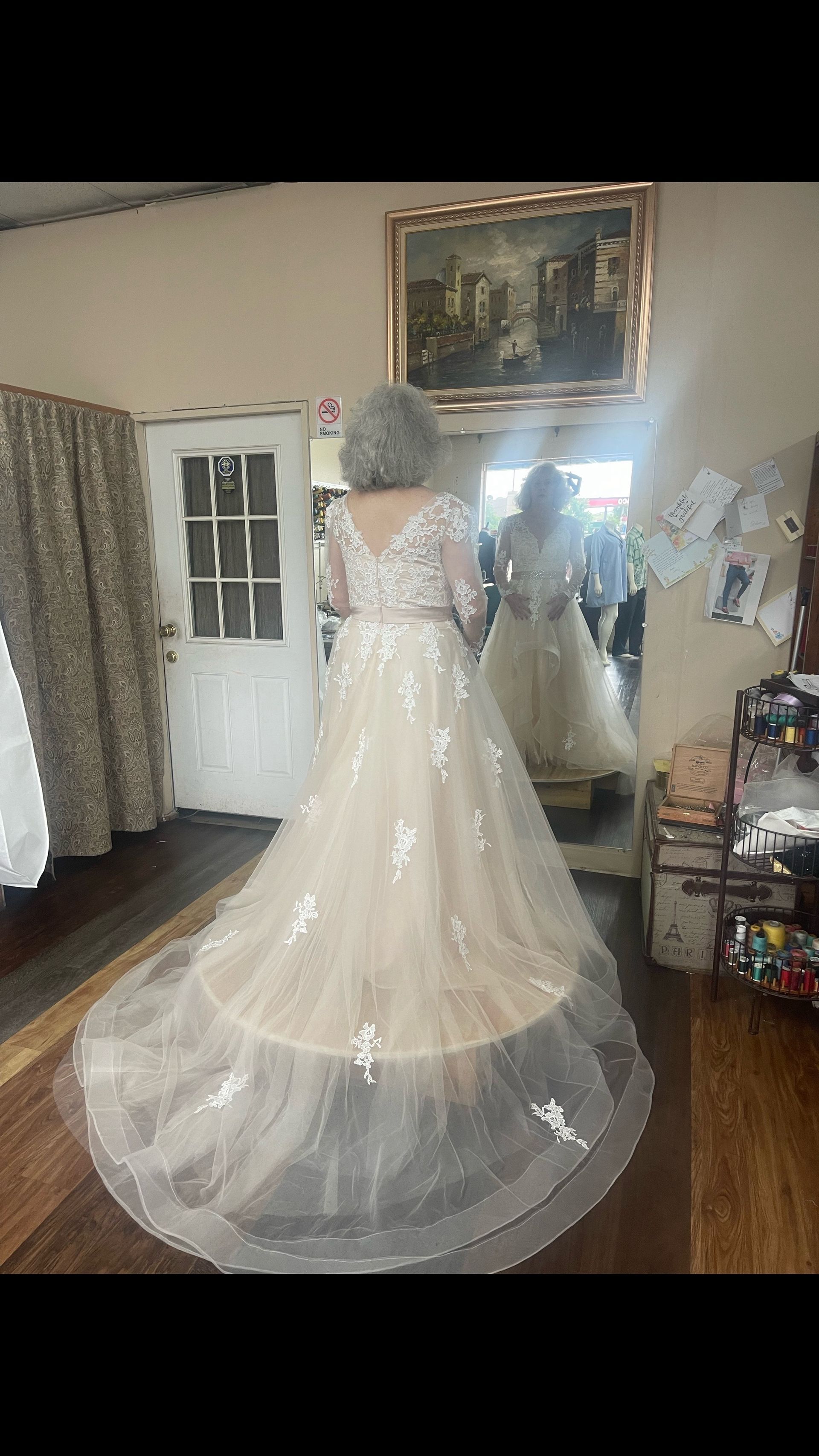 A woman is trying on a wedding dress in front of a mirror.