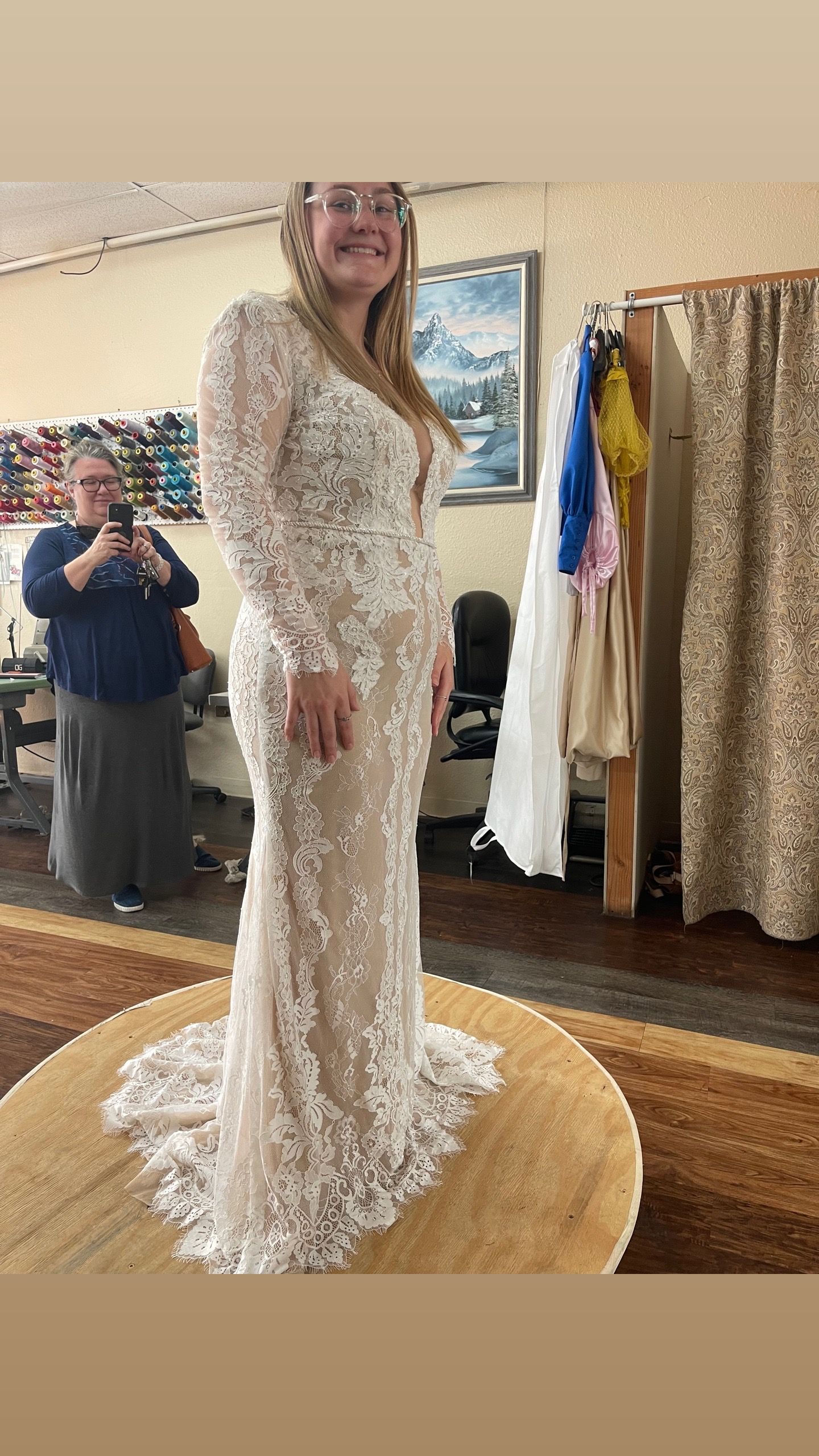 A woman is trying on a wedding dress in a dressing room.