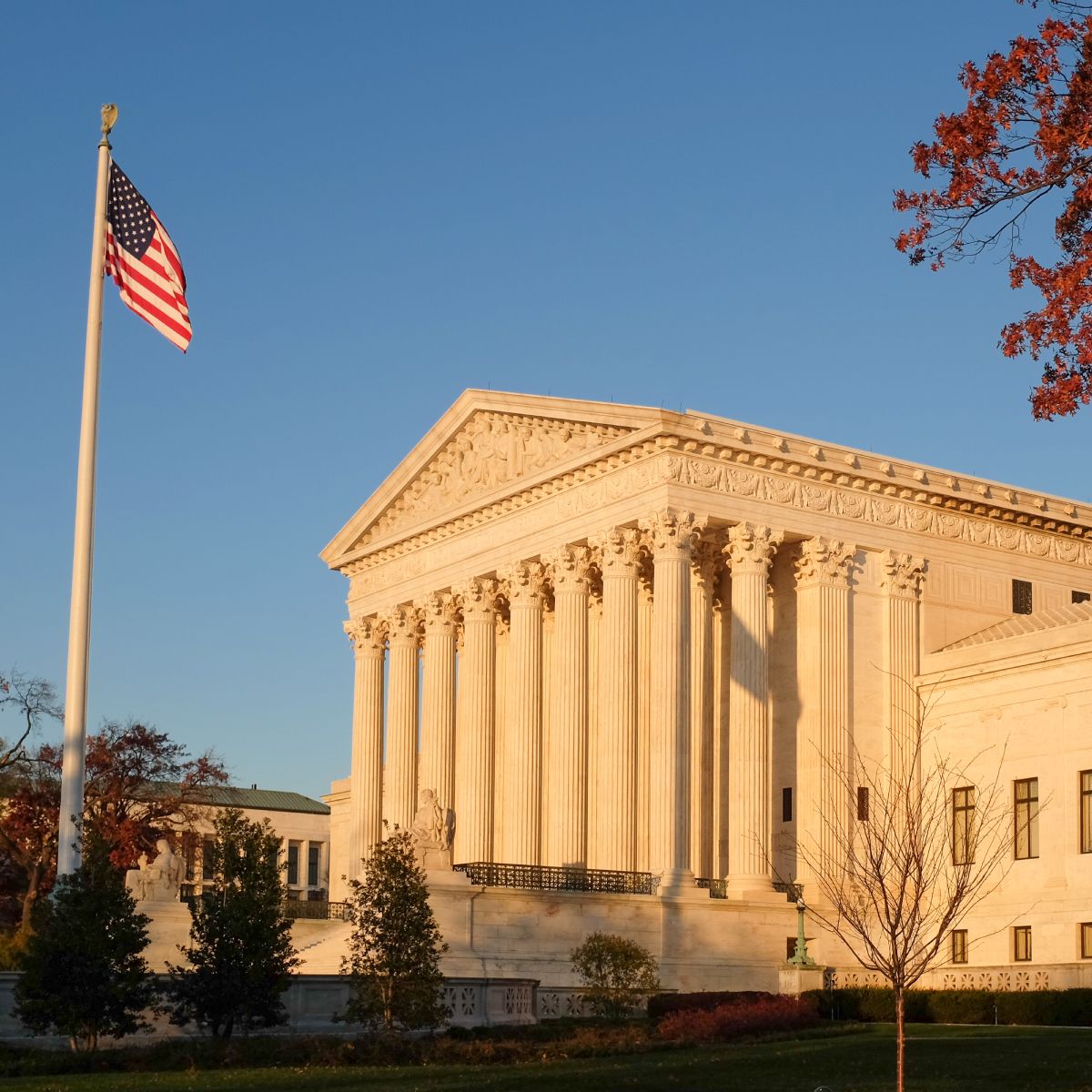 An american flag is flying in front of the supreme court building