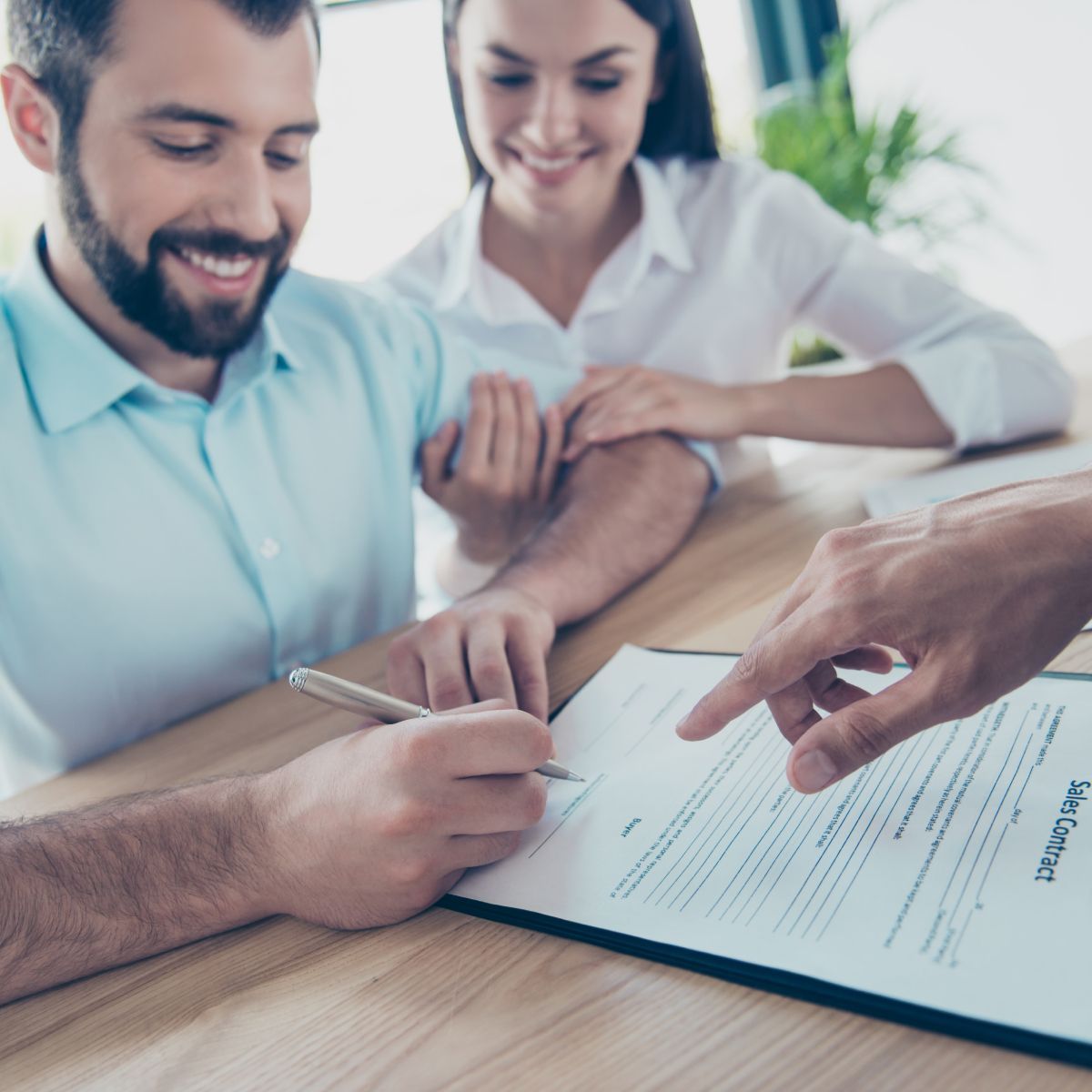 A man and a woman are sitting at a table signing a document.