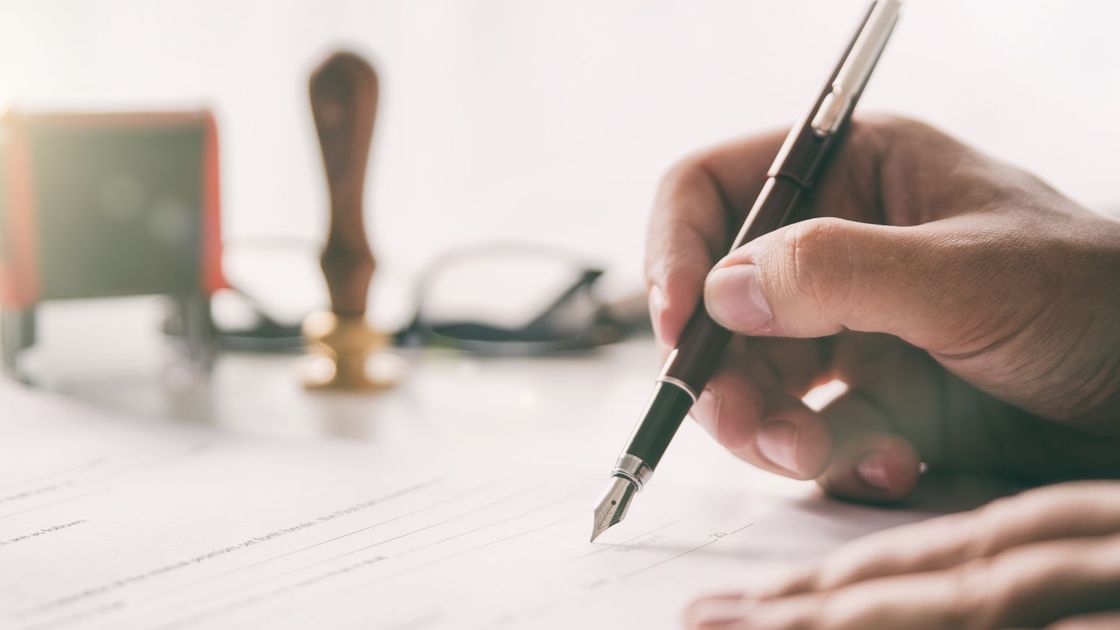 A person is writing on a piece of paper with a fountain pen.