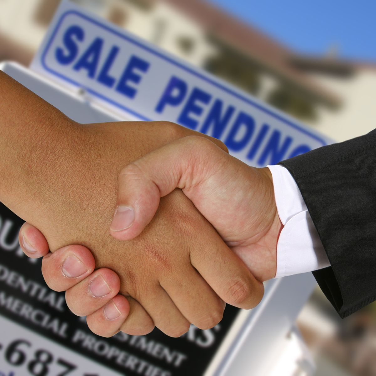 Two people shaking hands in front of a sale pending sign