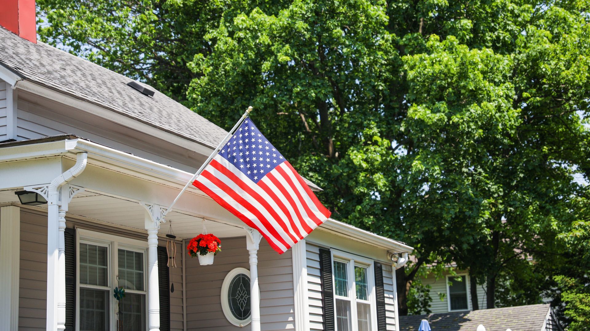 An american flag is flying on the porch of a house.