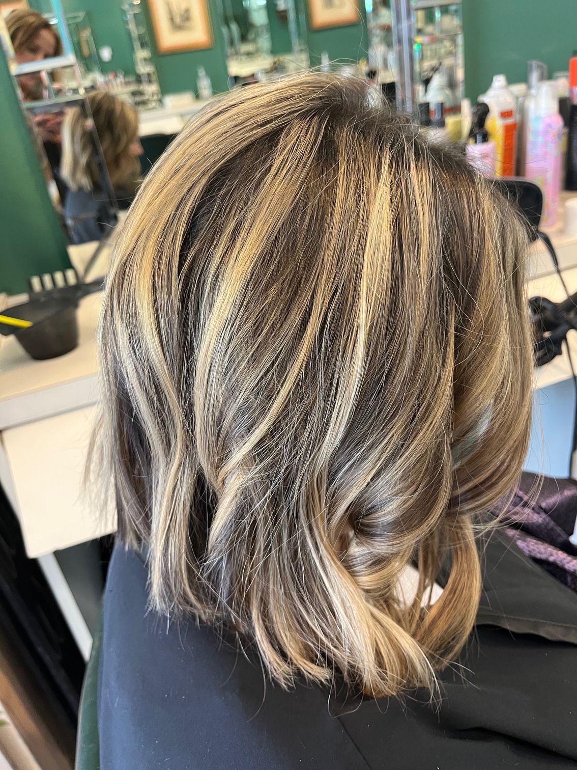 Shoulder-length hair with blonde highlights and brown lowlights in a salon setting.