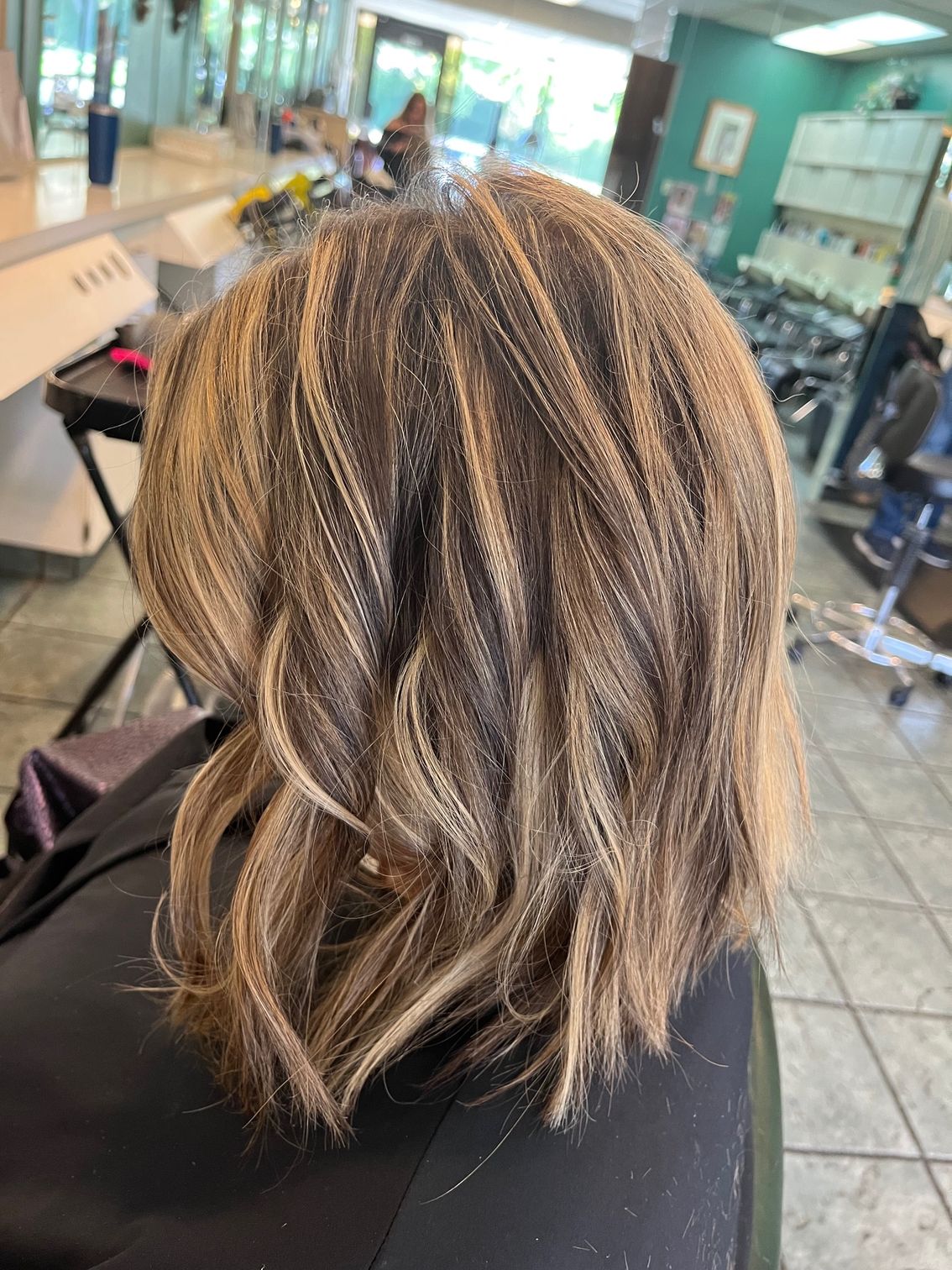 Woman with blonde highlights in a salon, wavy bob hairstyle.